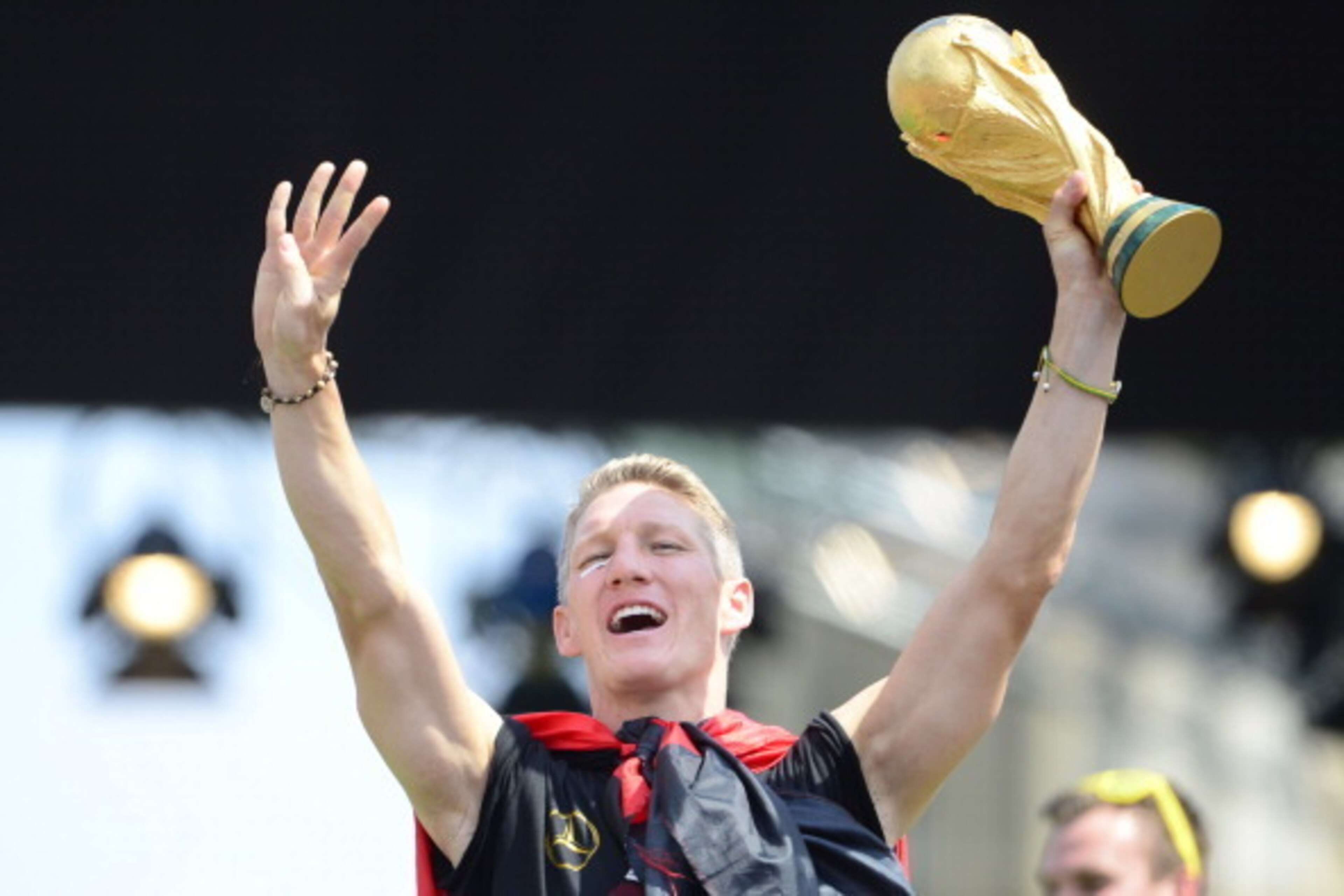 Germany's national football team's midfielder Bastian Schweinsteiger holds the trophy as he celebrates their FIFA World Cup 2014 title at a victory parade in front of fans on July 15, 2014 at Berlin's landmark Brandenburg Gate. Germany won their fourth Wo