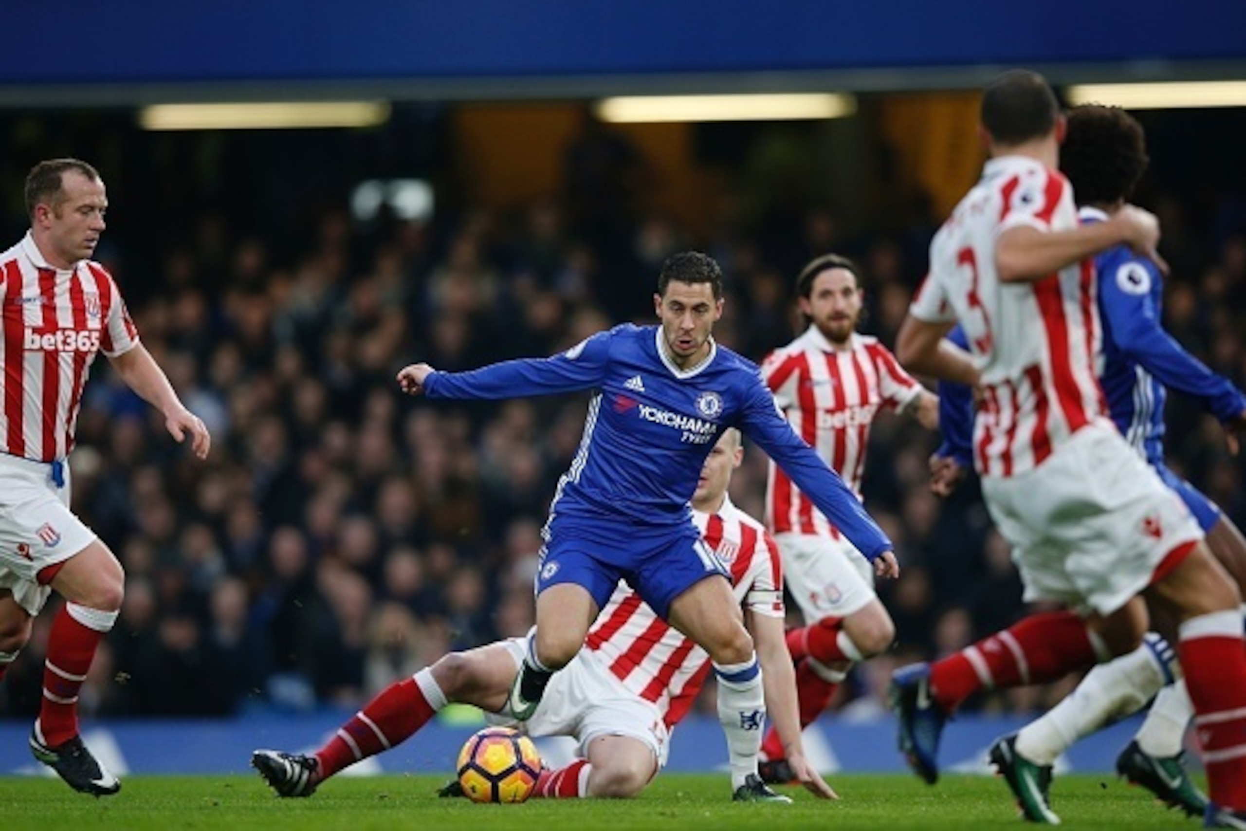 Chelsea's Belgian midfielder Eden Hazard (C) dribbles through the Stoke midfield during the English Premier League football match between Chelsea and Stoke City at Stamford Bridge in London on December 31, 2016. / AFP / Adrian DENNIS / RESTRICTED TO EDITO