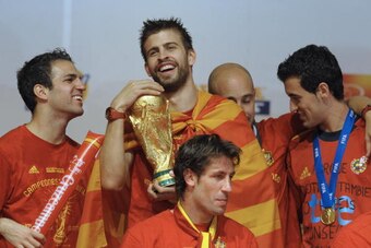 Spain's defender Gerard Pique (2ndL) hugs the trophy next to team mates on a stage set up for the Spanish team victory ceremony in Madrid on July 12, 2010 a day after they won the 2010 FIFA football World Cup match against the Netherlands in Johannesburg.