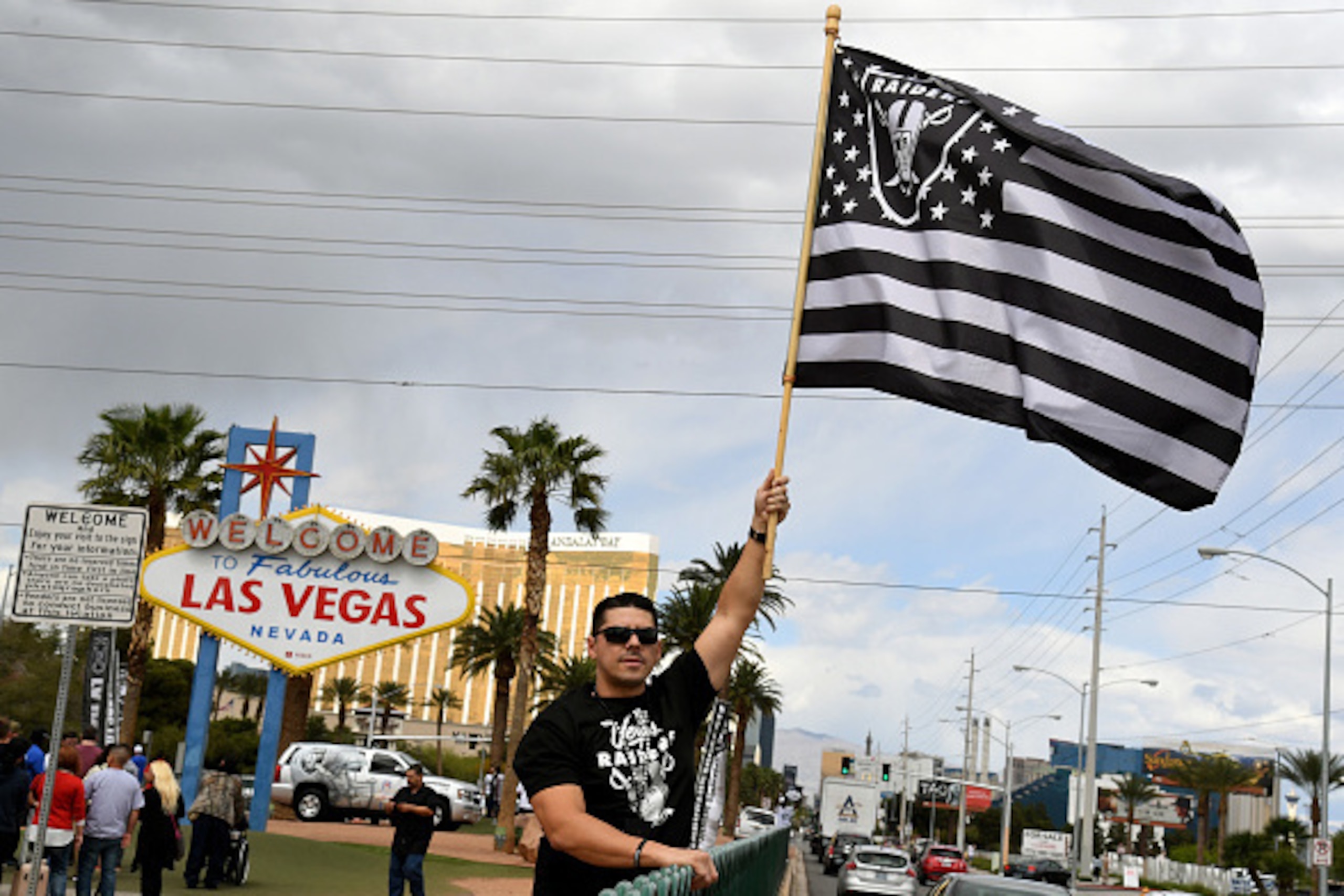 LAS VEGAS, NV - MARCH 27:  Oakland Raiders fan Matt Gutierrez of Nevada waves a Raiders flag in front of the Welcome to Fabulous Las Vegas sign after National Football League owners voted 31-1 to approve the team's application to relocate to Las Vegas dur