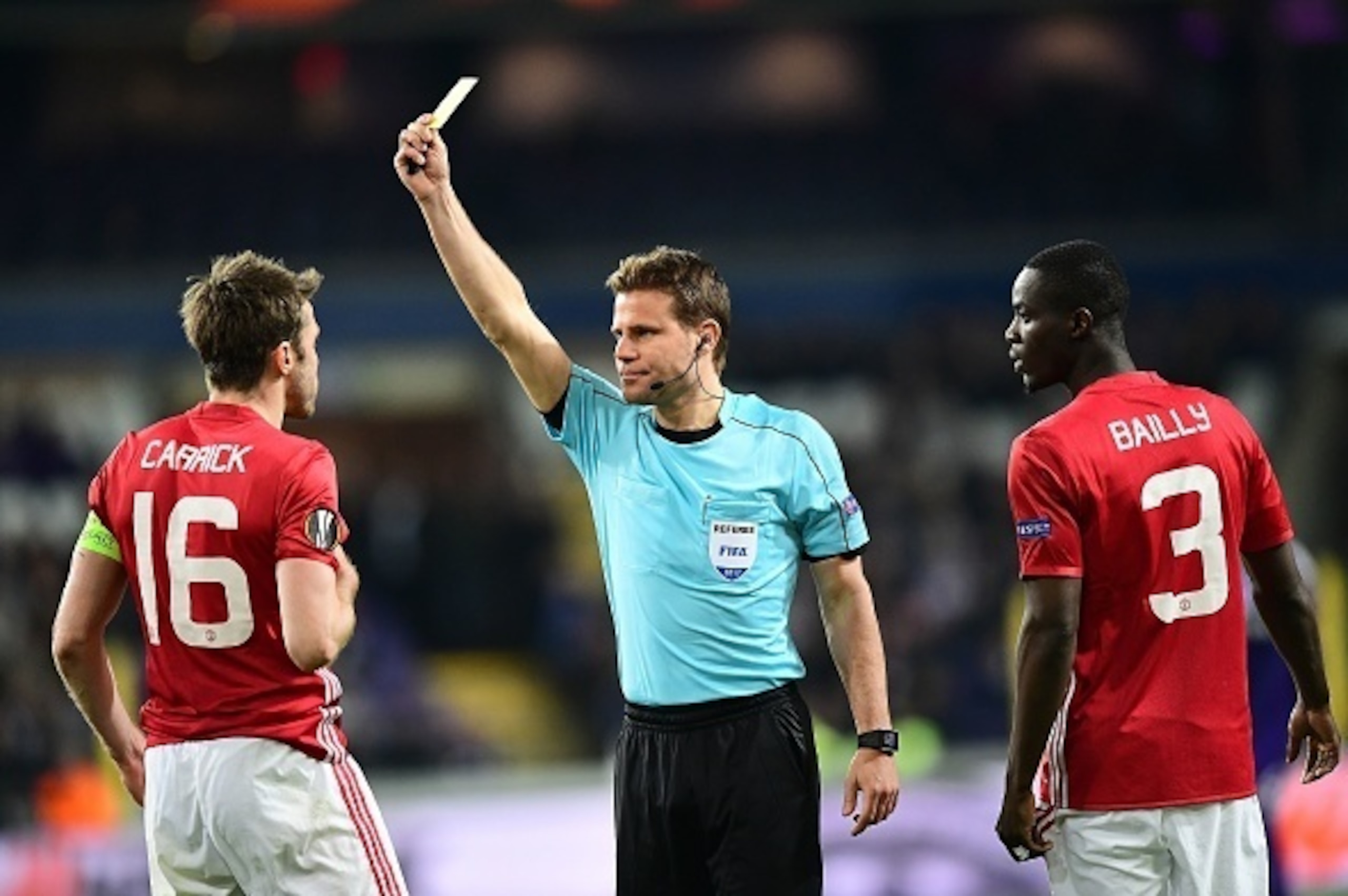 German referee Felix Brych (C) shows a yellow card to Manchester United's English midfielder Michael Carrick (L) as Manchester United's Ivorian defender Eric Bailly looks on during the UEFA Europa League match between Anderlecht and Manchester United at t German referee Felix Brych (C) shows a yellow card to Manchester United's English midfielder Michael Carrick (L) as Manchester United's Ivorian defender Eric Bailly looks on during the UEFA Europa League match between Anderlecht and Manchester United at t
