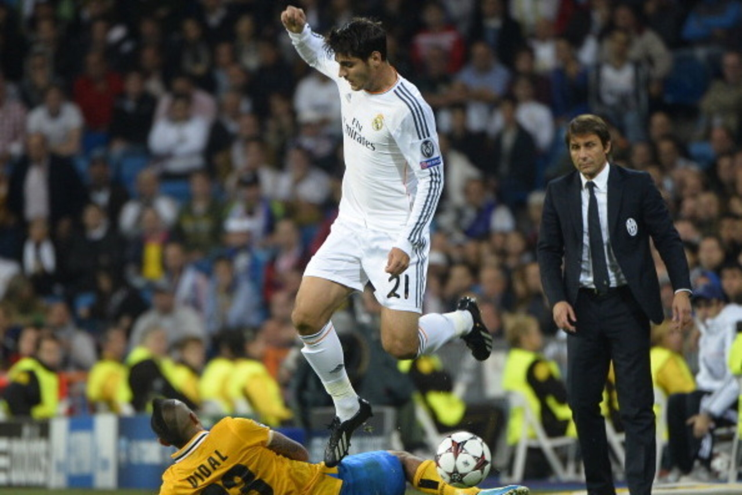 Real Madrid's forward Alvaro Morata (top) vies with Juventus' Chilean midfielder Arturo Erasmo Pardo Vidal (L) near to Juventus' coach Antonio Conte (R) during the UEFA Champions League Group B football match Real Madrid CF vs Juventus at the Santiago Ber