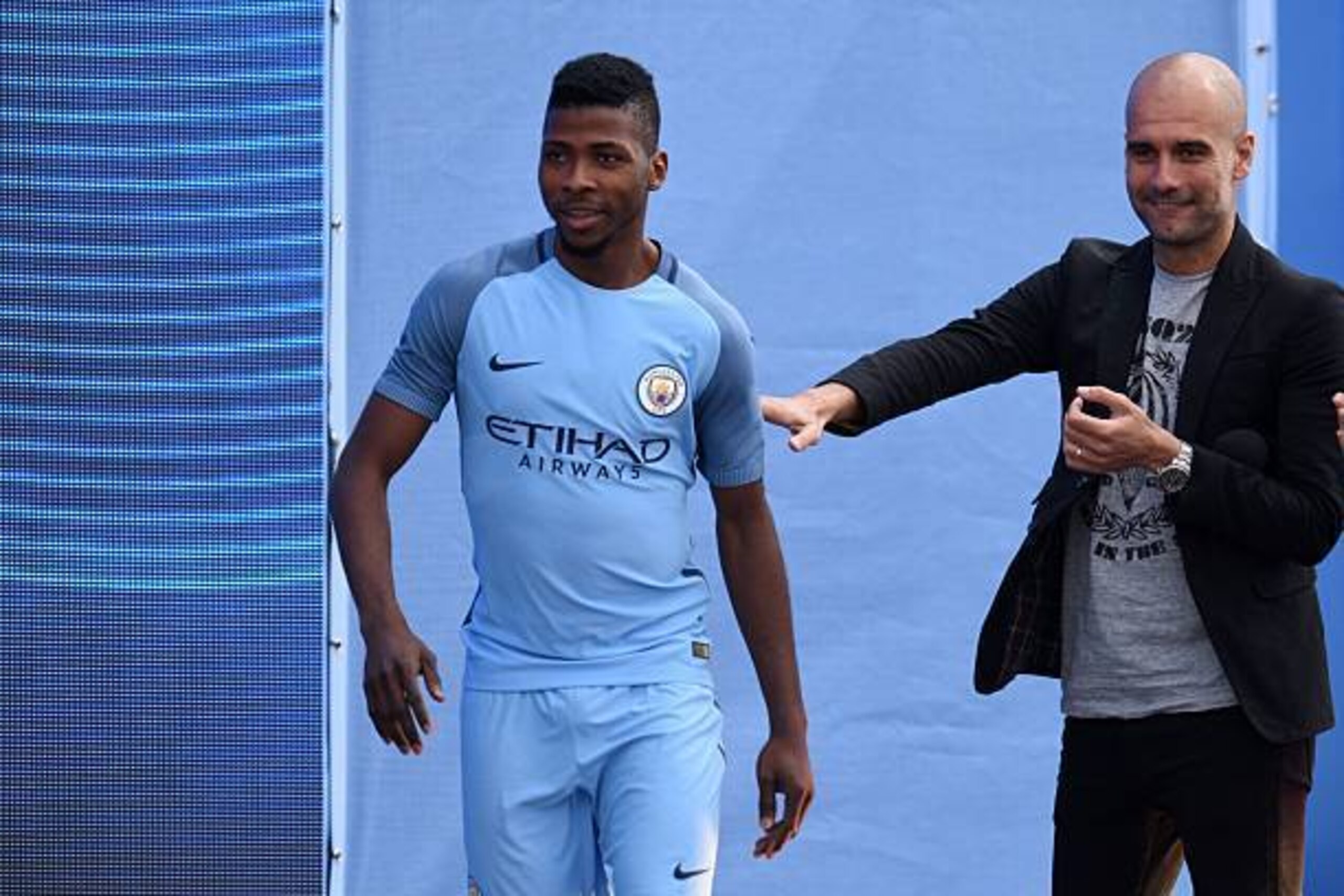 Spanish football manager Pep Guardiola (R) greets Manchester City's Nigerian striker Kelechi Iheanacho (L) as Guardiola is officially unveiled as the club's new manager at the City Football Academy in Manchester, north west England on July 3, 2016. / AFP 