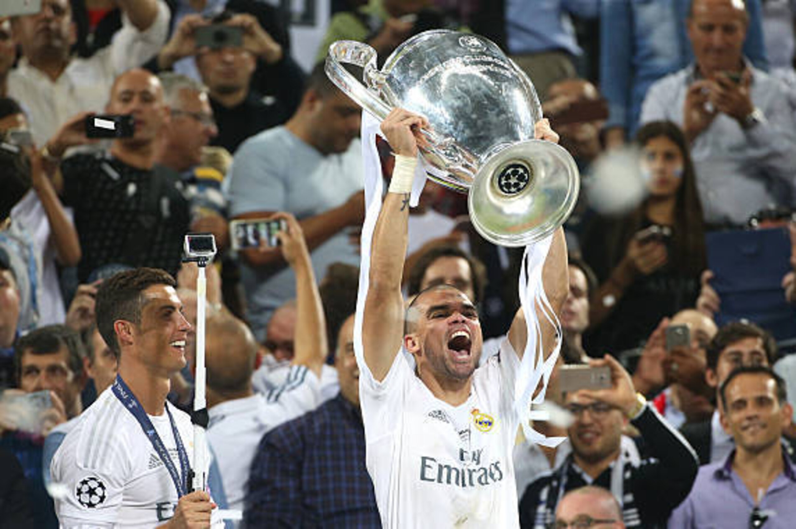 MILAN, ITALY - MAY 28: Pepe of Real Madrid hold the cup while Cristiano Ronaldo of Real Madrid looks on during the trophy ceremony following winning the UEFA Champions League final between Real Madrid and Club Atletico Madrid at Stadio Giuseppe Meazza, Sa