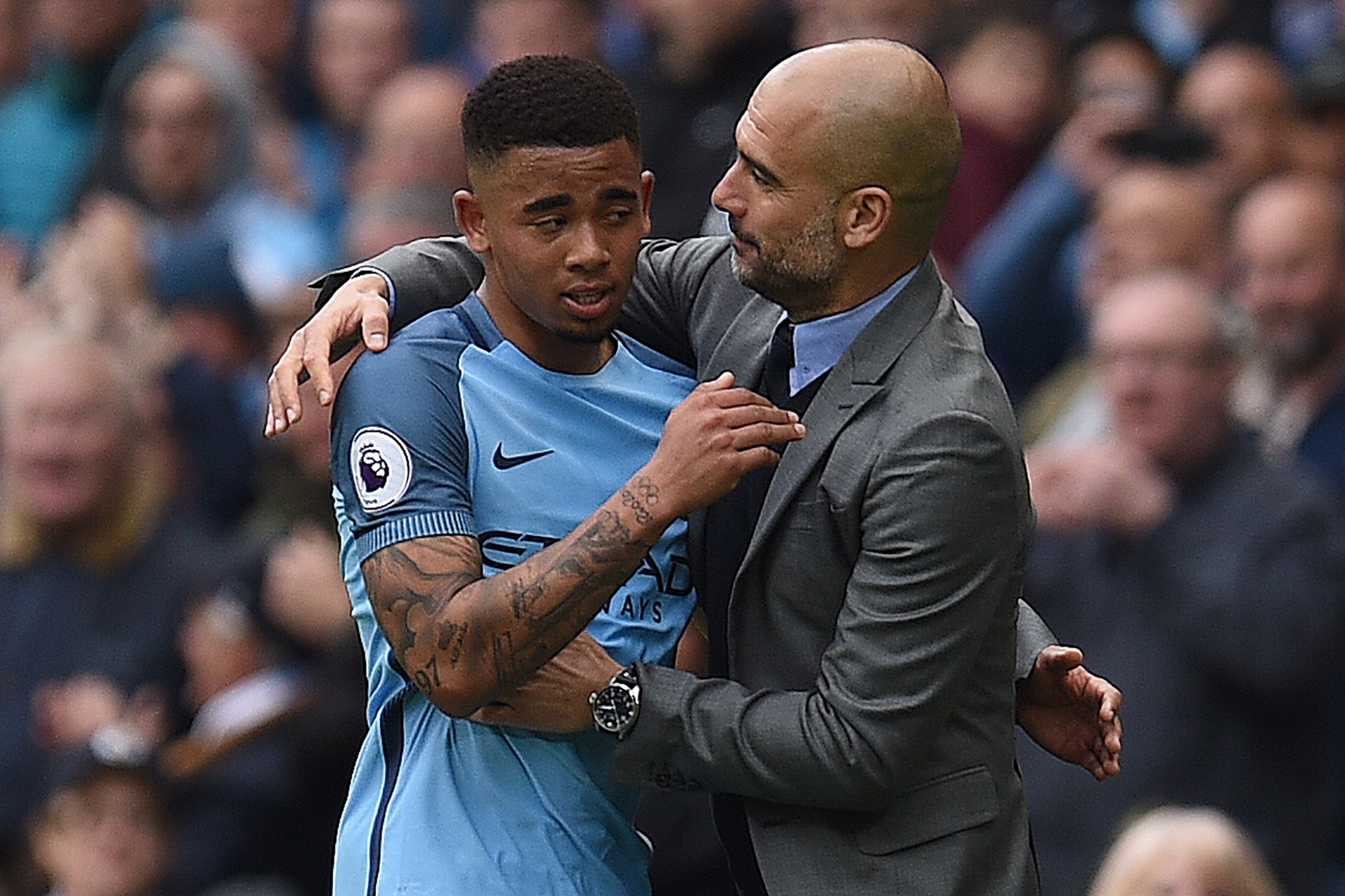 Manchester City's Brazilian striker Gabriel Jesus (L) is hugged by Manchester City's Spanish manager Pep Guardiola as he substituted off of the pitch during the English Premier League football match between Manchester City and Crystal Palace at the Etihad