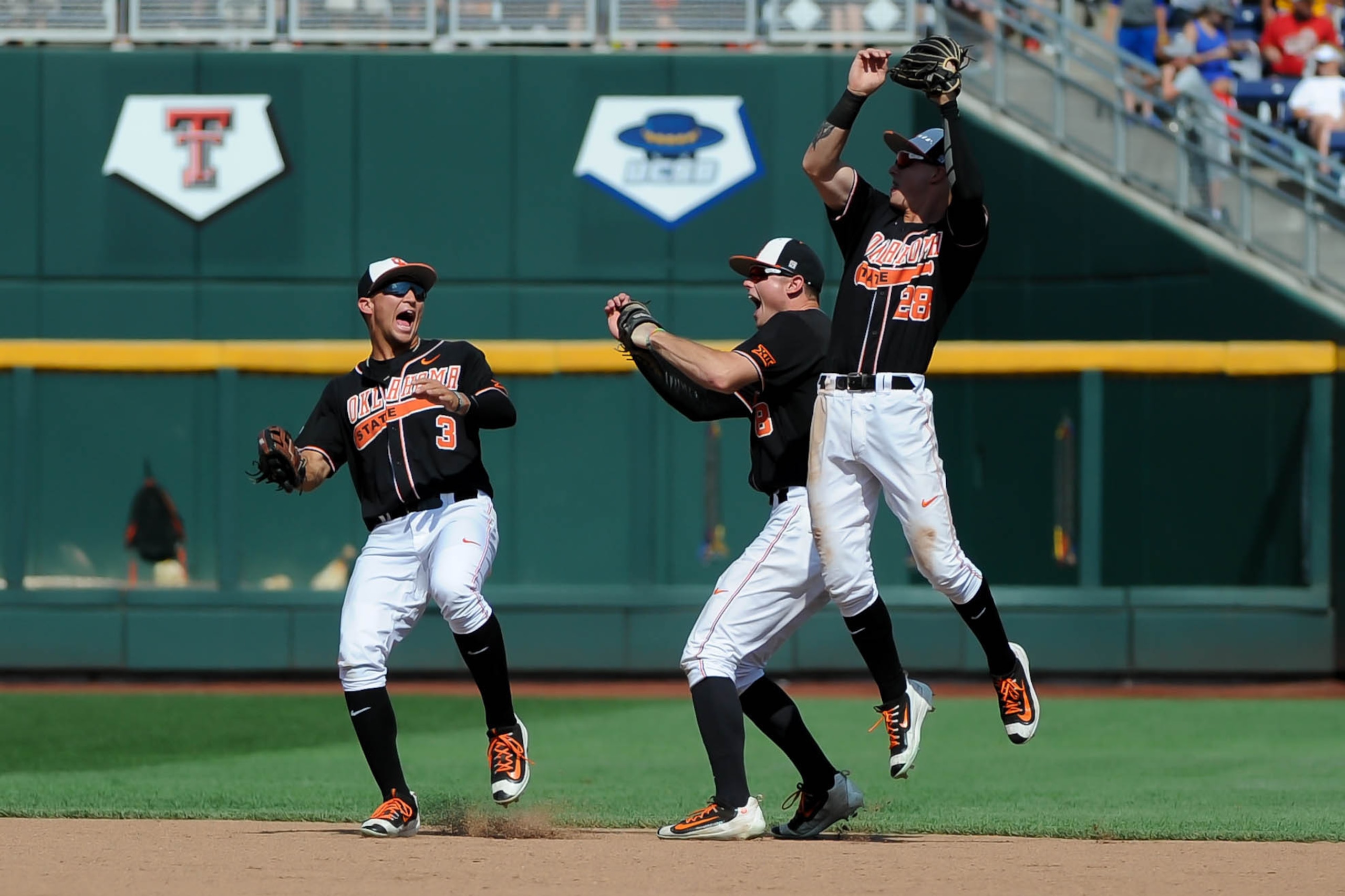 Jun 18, 2016; Omaha, NE, USA; Oklahoma State Cowboys infielder Corey Hassel (28), outfielder Ryan Sluder (8) and outfielder Garrett McCain (3) celebrate after the final out against the UC Santa Barbara Gauchos in the 2016 College World Series at TD Amerit