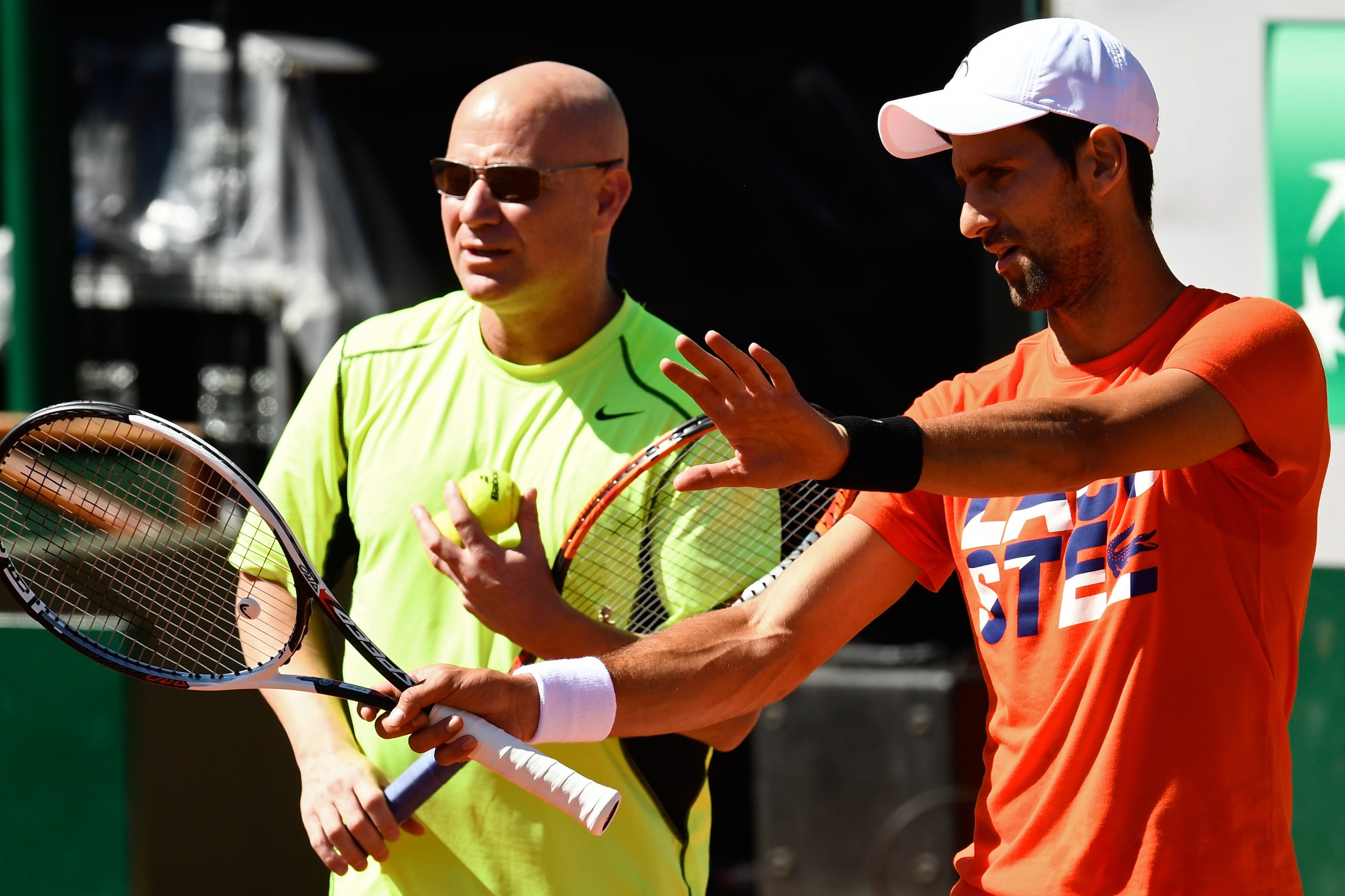 Serbia's player Novak Djokovic (R) and his coach Andre Agassi of the US attend a training session ahead of the Roland Garros 2017 French Tennis Open on May 26, 2017 in Paris.  / AFP PHOTO / CHRISTOPHE SIMON        (Photo credit should read CHRISTOPHE SIMO