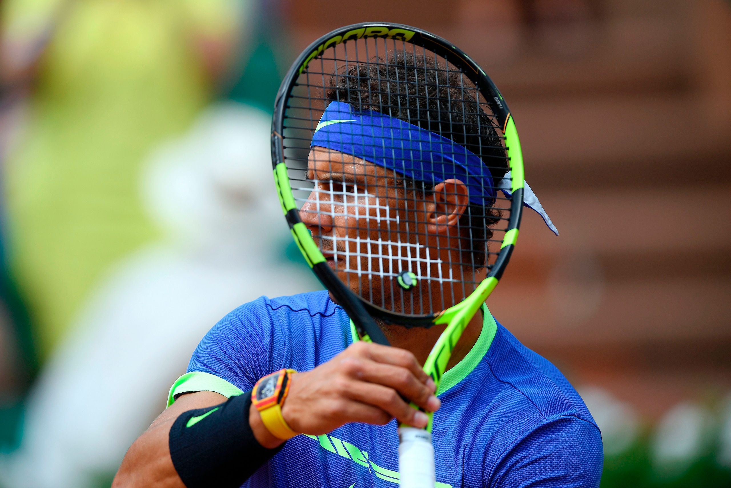 Spain's Rafael Nadal holds his racket in front of his face as he plays against France's Benoit Paire during their tennis match at the Roland Garros 2017 French Open on May 29, 2017 in Paris.  / AFP PHOTO / Lionel BONAVENTURE        (Photo credit should re