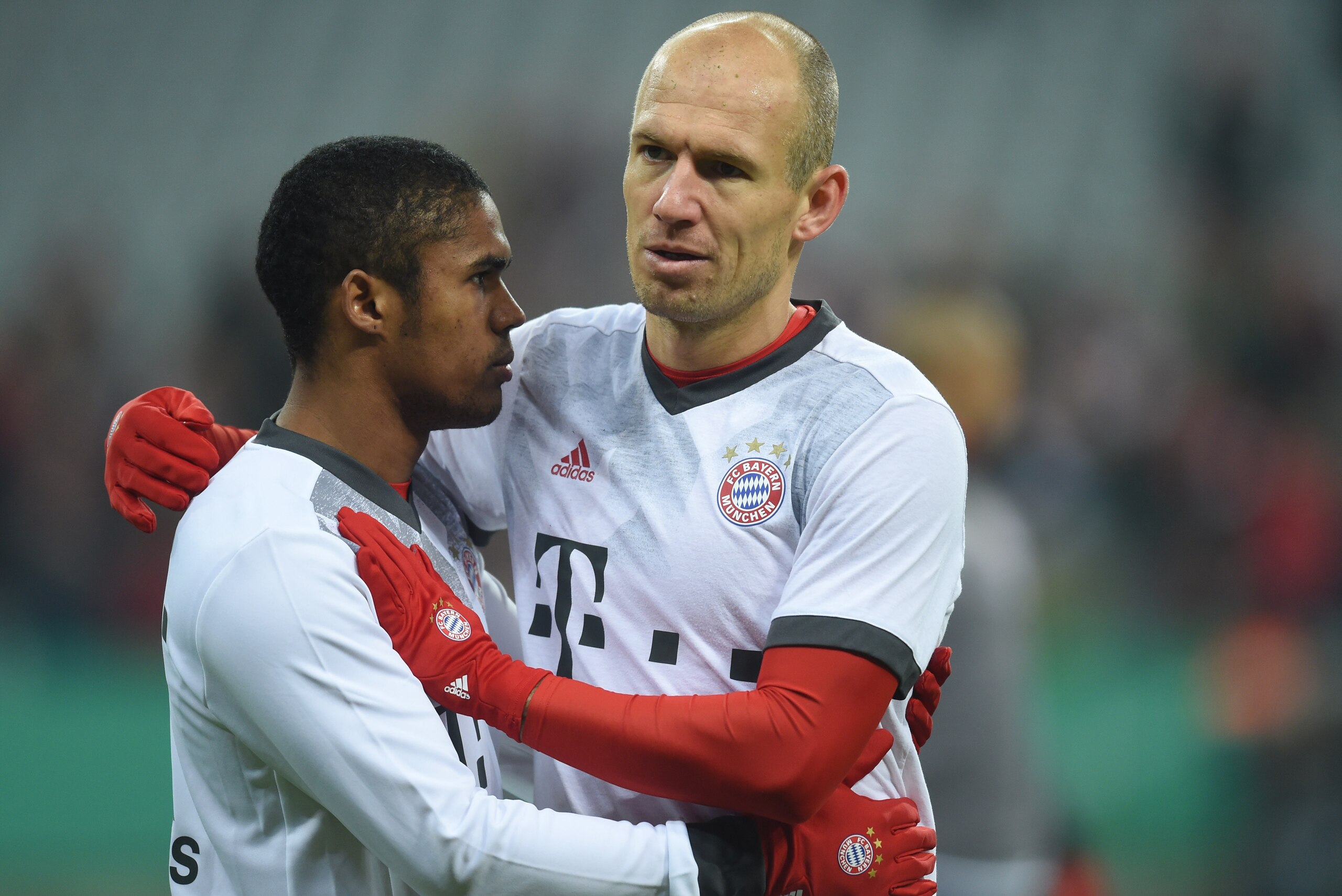 Bayern Munich's Dutch midfielder Arjen Robben (R) embraces his teammate Bayern Munich's Brazilian midfielder Douglas Costa (L) ahead of the German Cup DFB Pokal Round of 16 football match FC Bayern Munich v VFL Wolfburg in Munich, southern Germany on Febr