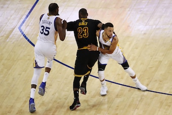OAKLAND, CA - JUNE 04: LeBron James #23 of the Cleveland Cavaliers attempts to run past Kevin Durant #35 and Stephen Curry #30 of the Golden State Warriors during the second half of Game 2 of the 2017 NBA Finals at ORACLE Arena on June 4, 2017 in Oakland,