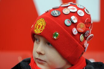 A young United fan shows off his badge collection.