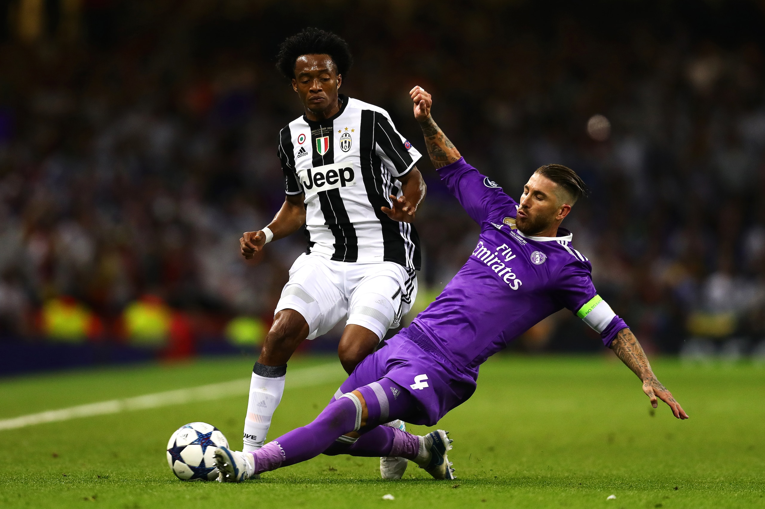 CARDIFF, WALES - JUNE 03: Juan Cuadrado of Juventus in action with Sergio Ramos of Real Madrid during the UEFA Champions League Final match between Juventus and Real Madrid at the National Stadium of Wales on June 3, 2017 in Cardiff, Wales. (Photo by Chri