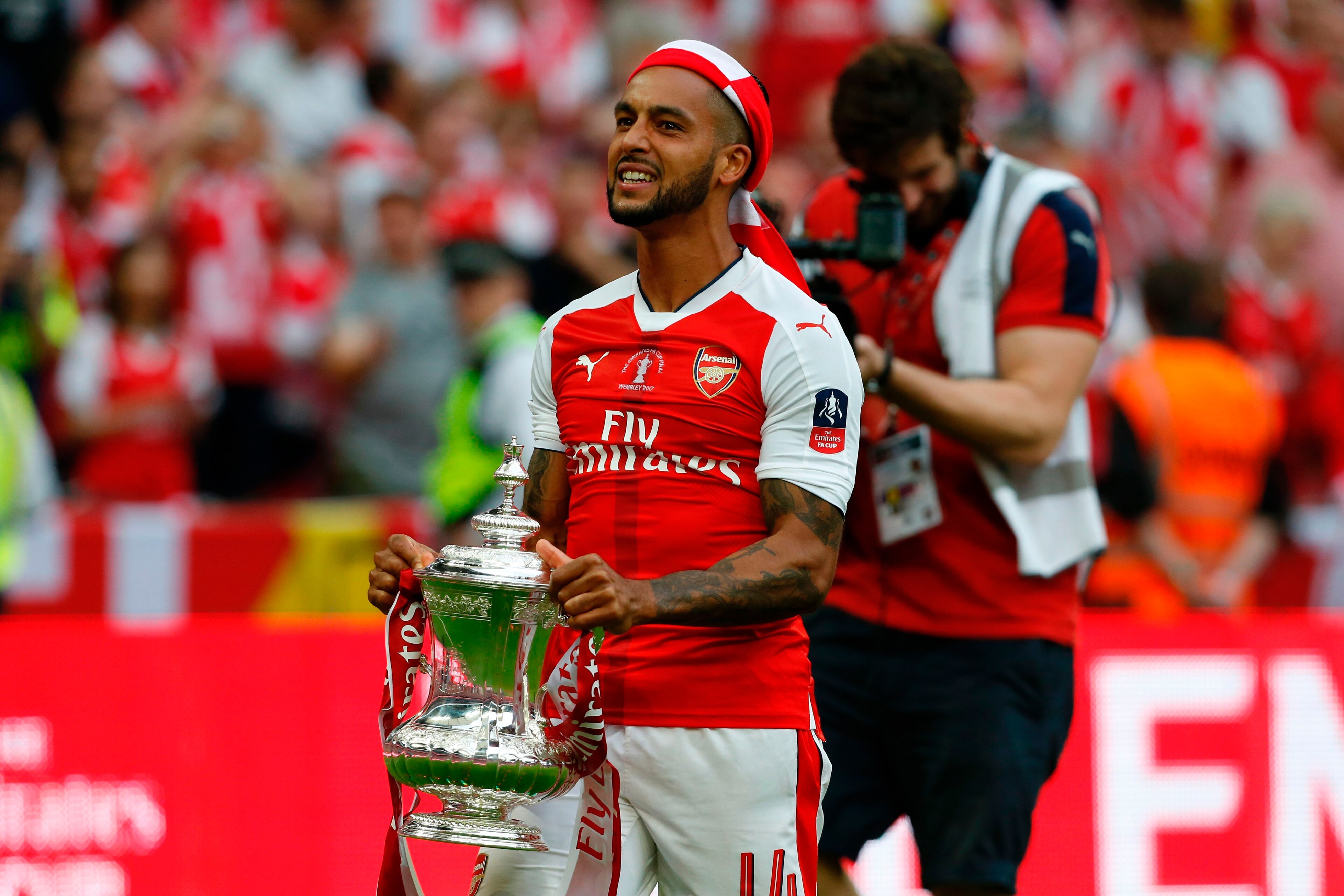 Arsenal's English midfielder Theo Walcott holds the FA Cup trophy as Arsenal players celebrate their victory over Chelsea on the pitch after the English FA Cup final football match between Arsenal and Chelsea at Wembley stadium in London on May 27, 2017.
