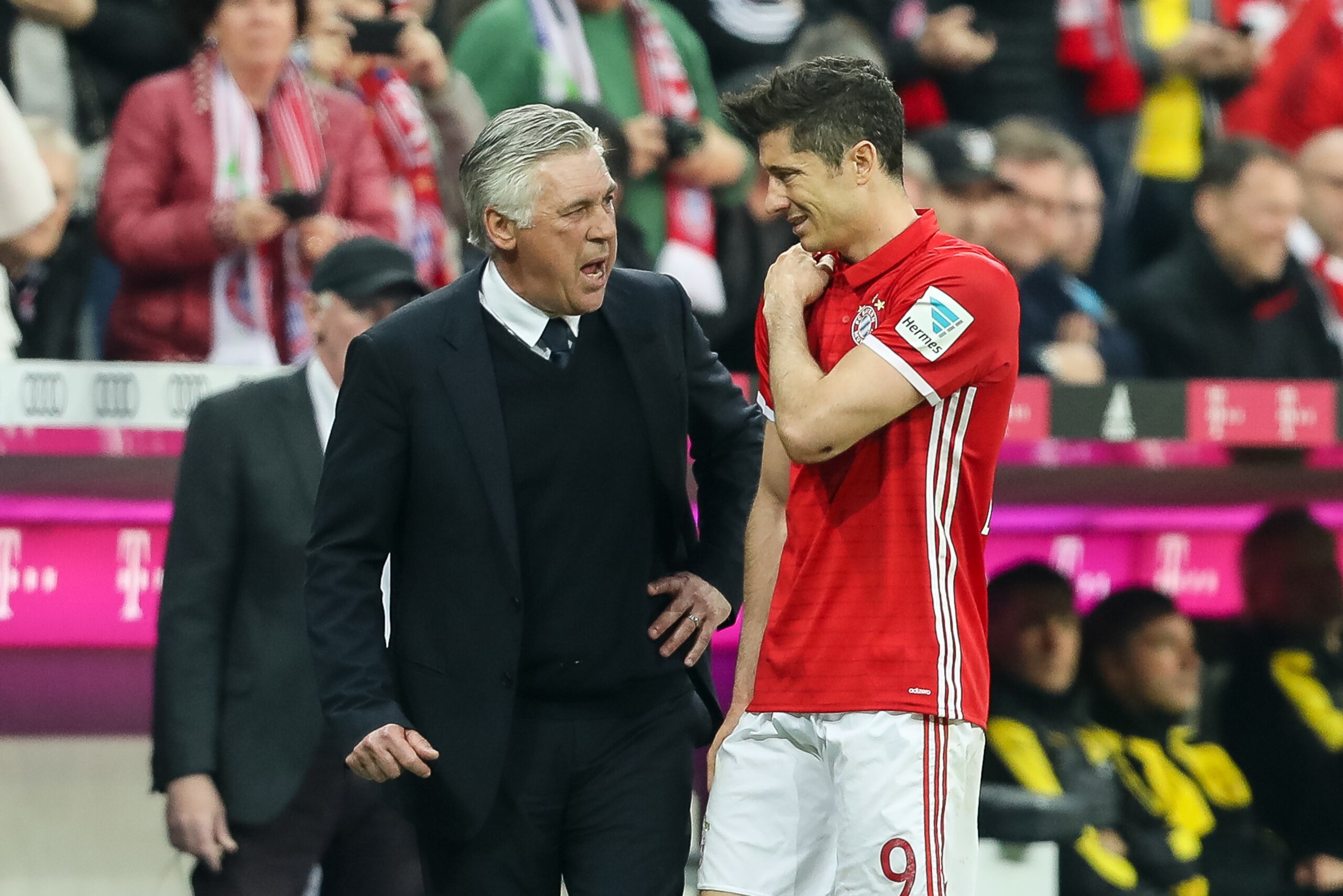 MUNICH, GERMANY - APRIL 08: Robert Lewandowski of Bayern Muenchen feels tha pain while being congratulated by Carlo Ancelotti head coach of Bayern Muenchen after being substituted during the Bundesliga match between Bayern Muenchen and Borussia Dortmund a