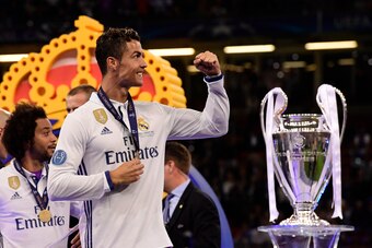 Real Madrid's Portuguese striker Cristiano Ronaldo celebrates next to the trophy after Real Madrid won the UEFA Champions League final football match between Juventus and Real Madrid at The Principality Stadium in Cardiff, south Wales, on June 3, 2017. / 