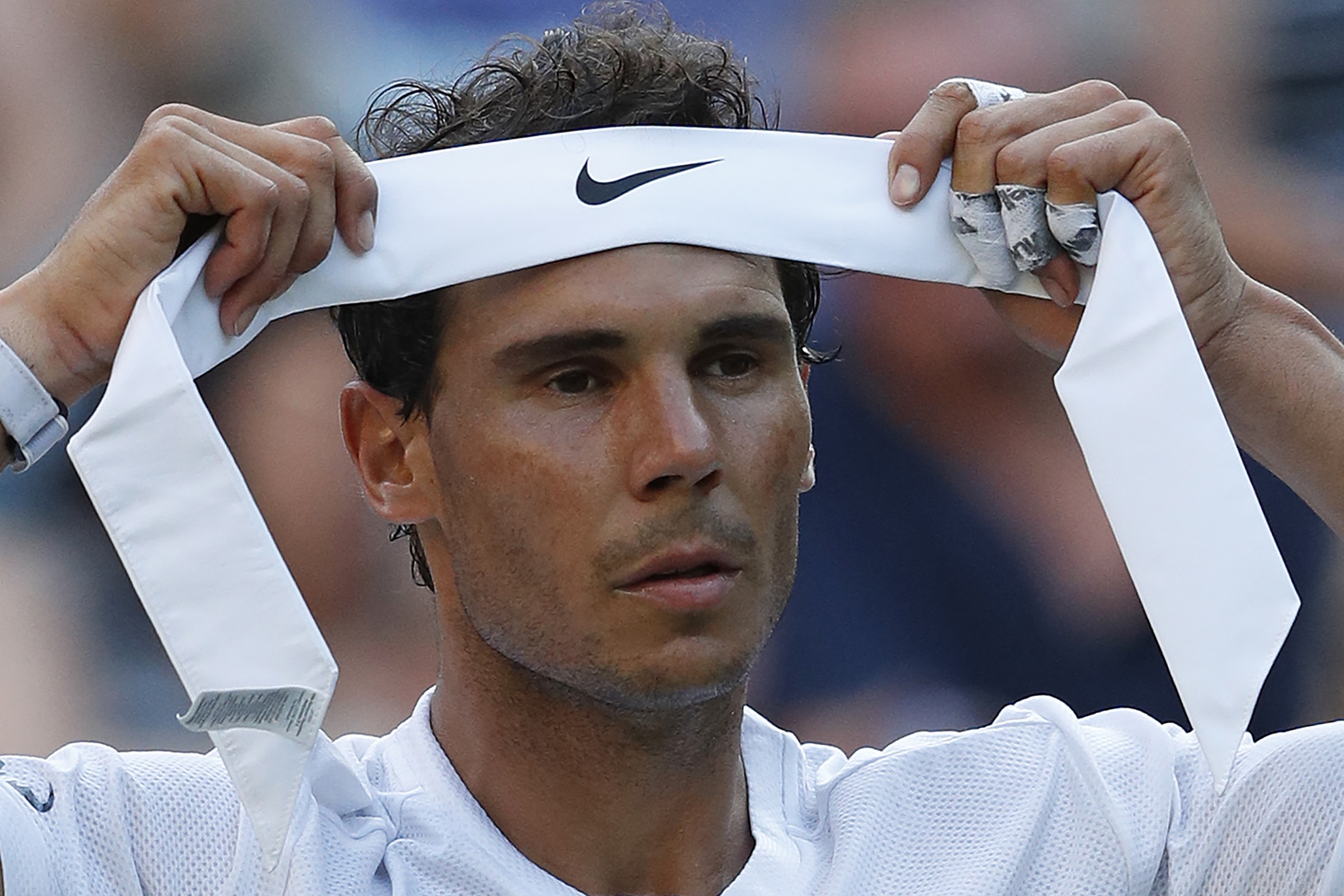 Spain's Rafael Nadal changes his head band during a break in play against US player Donald Young during their men's singles second round match on the third day of the 2017 Wimbledon Championships at The All England Lawn Tennis Club in Wimbledon, southwest