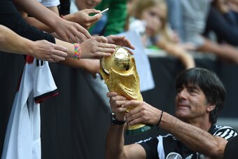 Germany's head coach Joachim Loew shows the world cup trophy to fans during a public training session of the German national football team in Duesseldorf, Germany on September 1, 2014. Germany's squad prepares for the upcoming friendly game against Argent