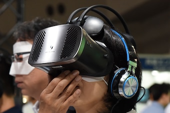 A woman attaches a 'IDEALENS K2+' VR device presented by VR Japan at the VR/AR World Exhibition as part of the Advanced Content Technology Expo in Tokyo on June 29, 2017.  / AFP PHOTO / Kazuhiro NOGI        (Photo credit should read KAZUHIRO NOGI/AFP/Gett