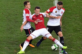 Arsenal player Granit Xhaka (C) is tackled by Western Sydney Wanderers players Steven Lustica (L) and Robert Cornthwaite (R) in their pre-season football friendly played in Sydney on July 15, 2017. / AFP PHOTO / WILLIAM WEST / -- IMAGE RESTRICTED TO EDITO