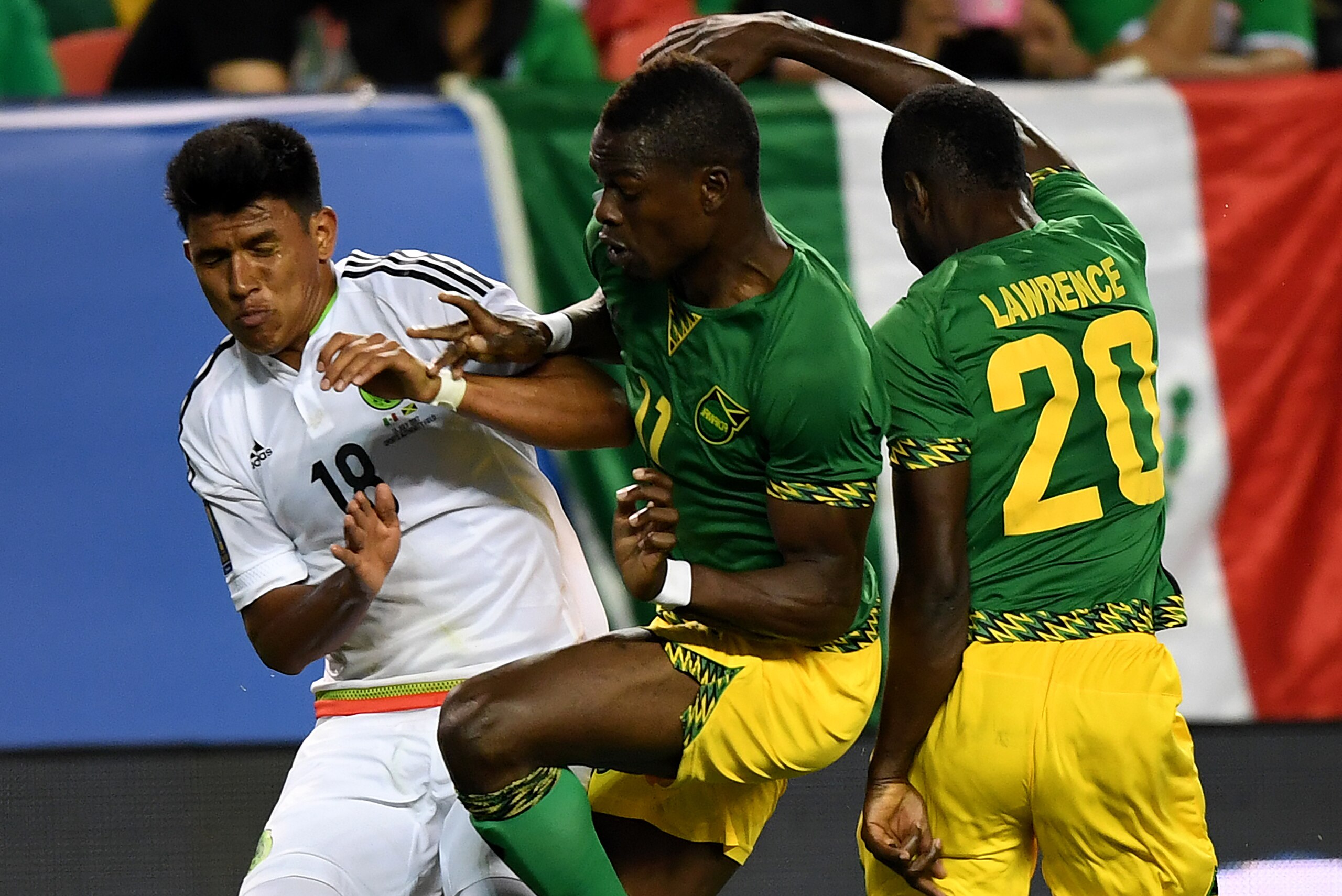 Mexico's Jesus Gallardo (L) is tackled by Jamaica's Cory Burke (C) and Kemar Lawrence (R) during the Mexico vs Jamaica CONCACAF Group C Gold Cup soccer game on July 13, 2017 at Sports Authority Field at Mile High in Denver, Colorado.  / AFP PHOTO / MARK R
