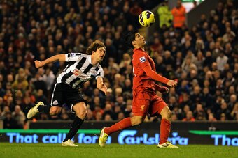 Liverpool's Uruguayan striker Luis Suarez (R) beats Newcastle United's Argentinian defender Fabricio Coloccini (L) on his way to scoring their equalizing goal during the English Premier League football match between Liverpool and Newcastle United at Anfie