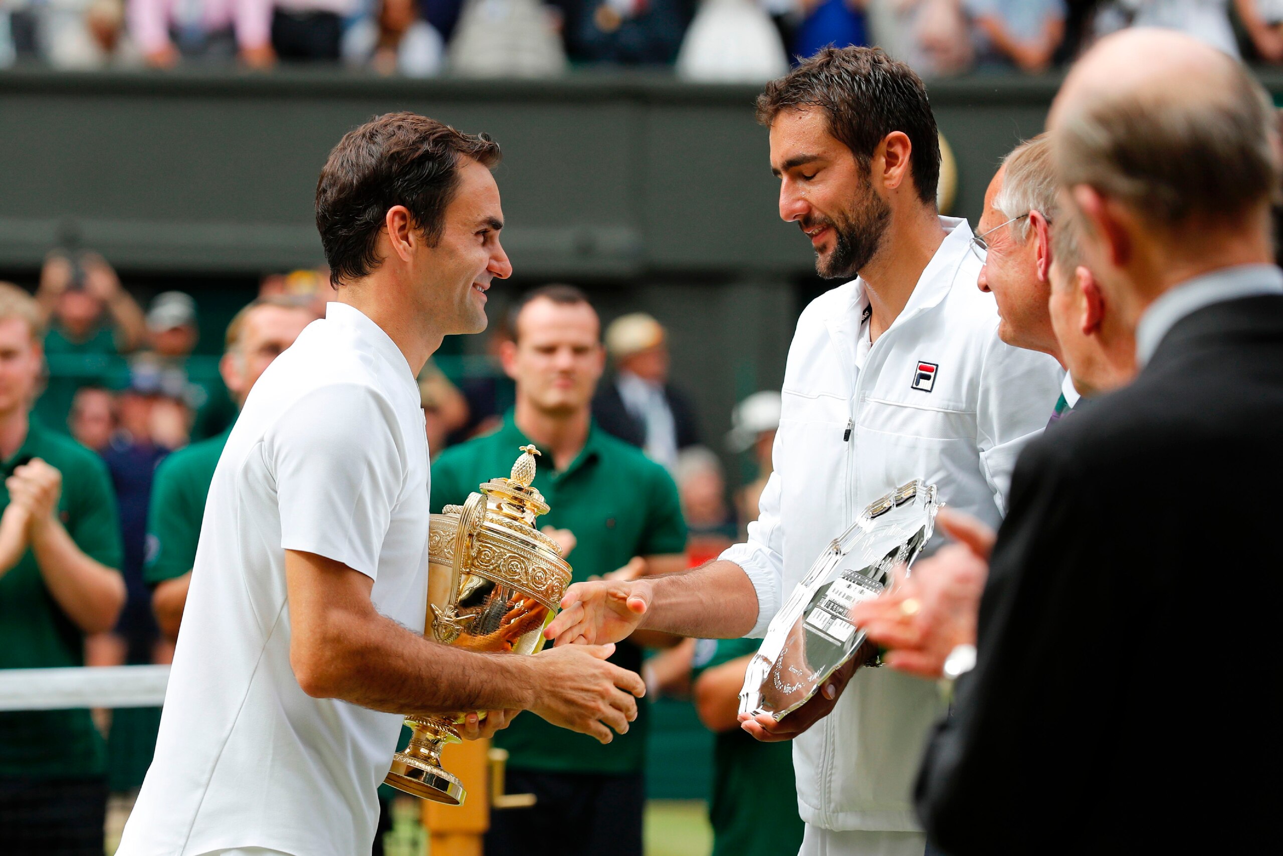 Switzerland's Roger Federer (L) shakes hands with Croatia's Marin Cilic pose with their trophies after Federer won their men's singles final match, during the presentation on the last day of the 2017 Wimbledon Championships at The All England Lawn Tennis 