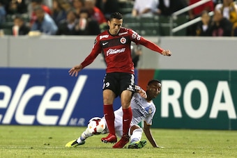 LOS ANGELES, CA - MARCH 12:  James Riley #26 of the Los Angeles Galaxy tackles Herculez Gomez #9 of Club Tijuana in the second half during the CONCACAF Champions League Quarterfinal match at StubHub Center on March 12, 2014 in Los Angeles, California.  (P
