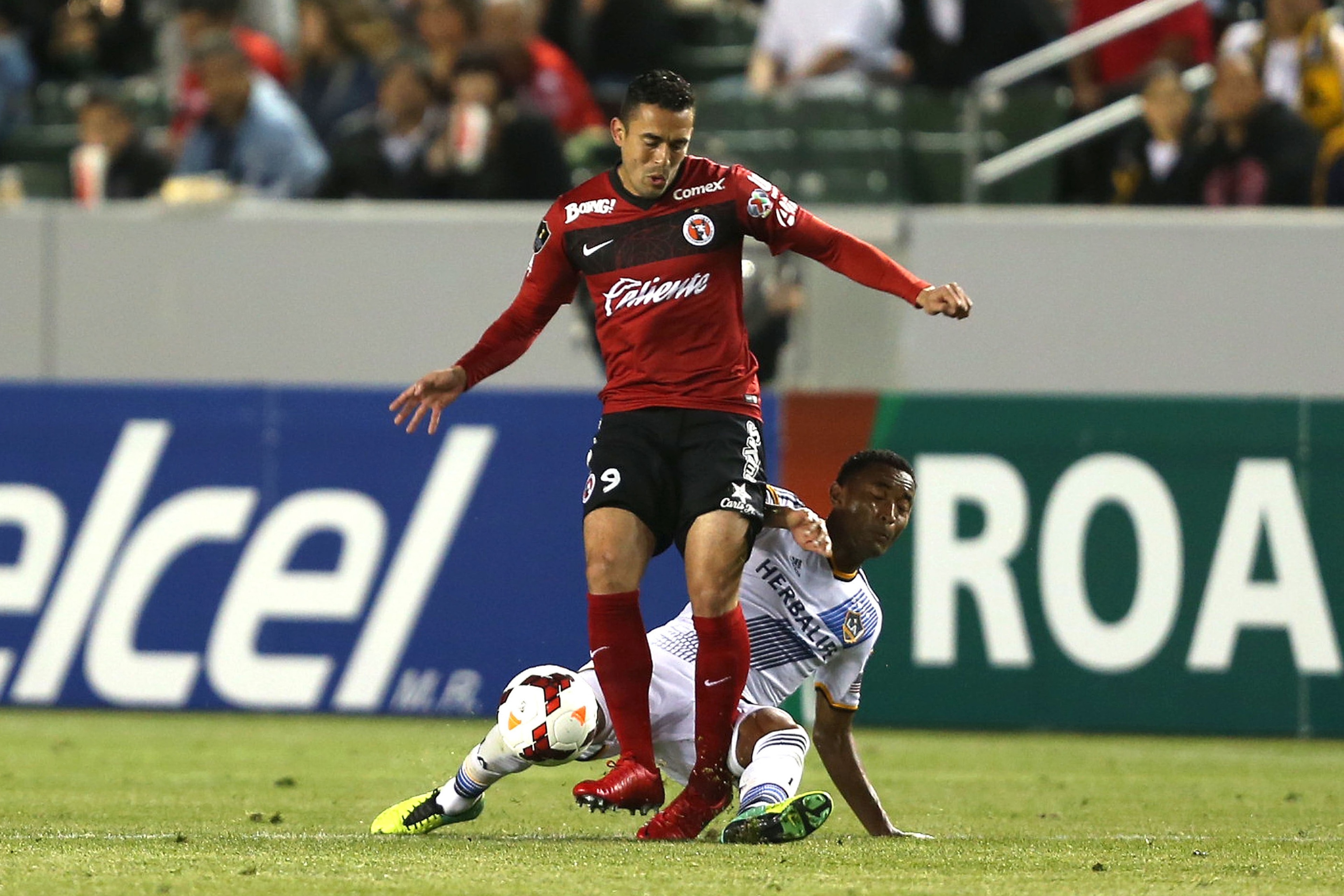 LOS ANGELES, CA - MARCH 12: James Riley #26 of the Los Angeles Galaxy tackles Herculez Gomez #9 of Club Tijuana in the second half during the CONCACAF Champions League Quarterfinal match at StubHub Center on March 12, 2014 in Los Angeles, California. (P LOS ANGELES, CA - MARCH 12: James Riley #26 of the Los Angeles Galaxy tackles Herculez Gomez #9 of Club Tijuana in the second half during the CONCACAF Champions League Quarterfinal match at StubHub Center on March 12, 2014 in Los Angeles, California. (P