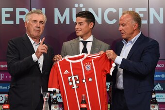 Colombian midfielder James Rodriguez (C), new recruit of German first division Bundesliga football club Bayern Munich, holds his new jersey as he poses with Bayern Munich's Italian head coach Carlo Ancelotti (L) and the club's CEO Karl-Heinz Rummenigge (R