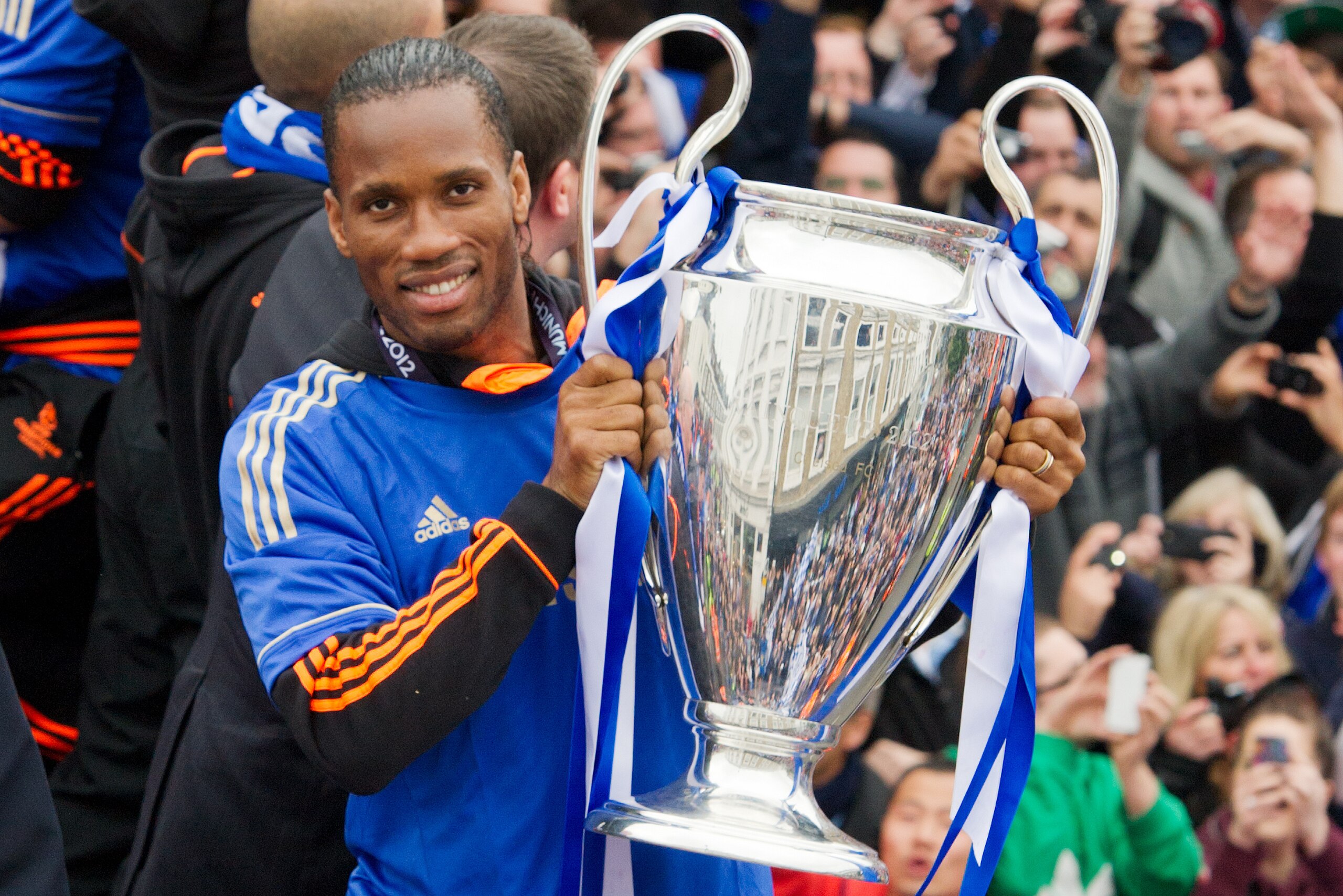 Chelsea football club player Didier Drogba holds the Champions League and FA Cup as the team rides during an open-top bus parade along Kings Road in west London on May 20, 2012.  Chelsea's dramatic win over Bayern Munich on penalties last night has result