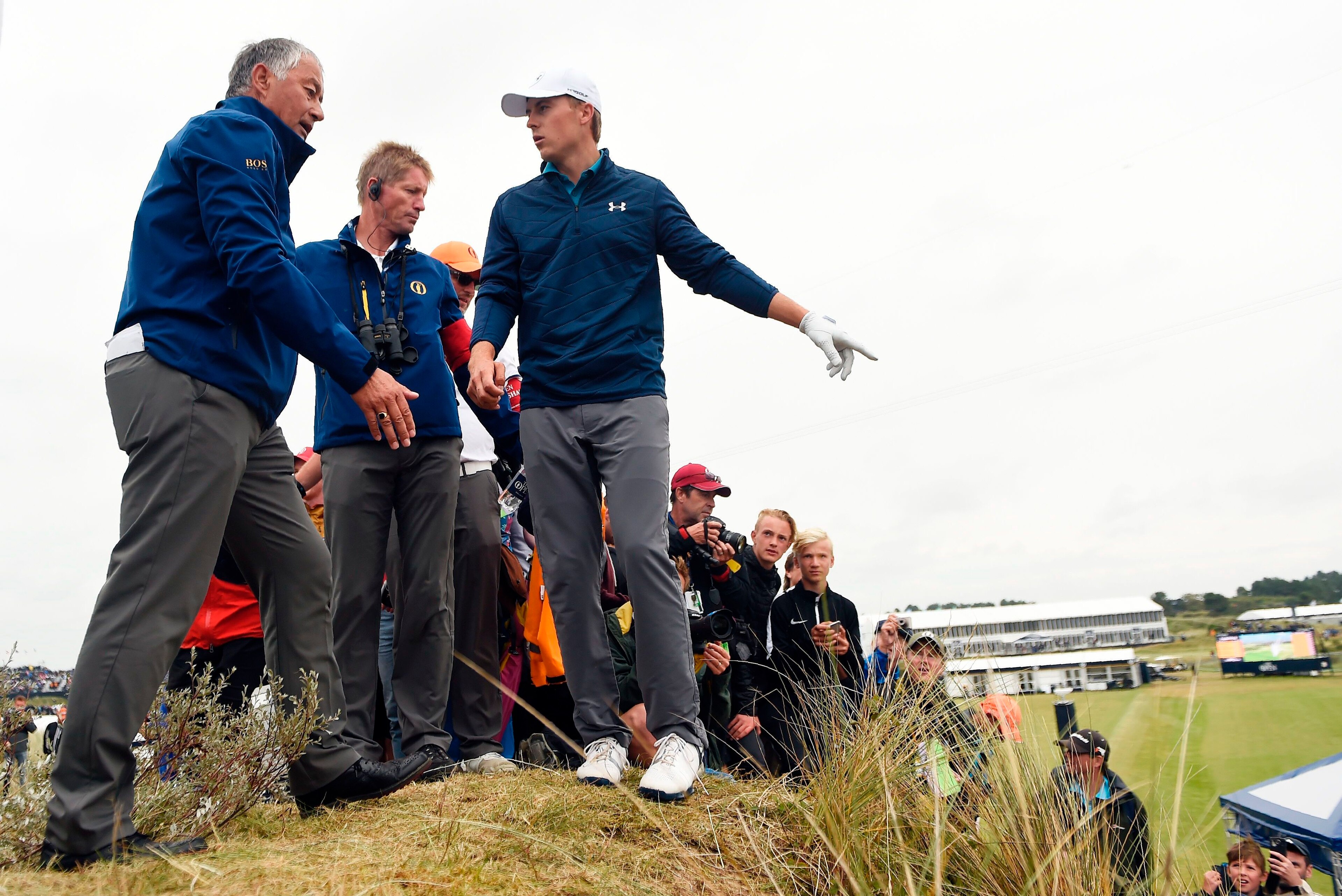 US golfer Jordan Spieth (C) discusses his options with a rules official after taking a penalty drop for having an unplayable lie on the 13th hole during his final round on day four of the 2017 Open Golf Championship at Royal Birkdale golf course near Sout