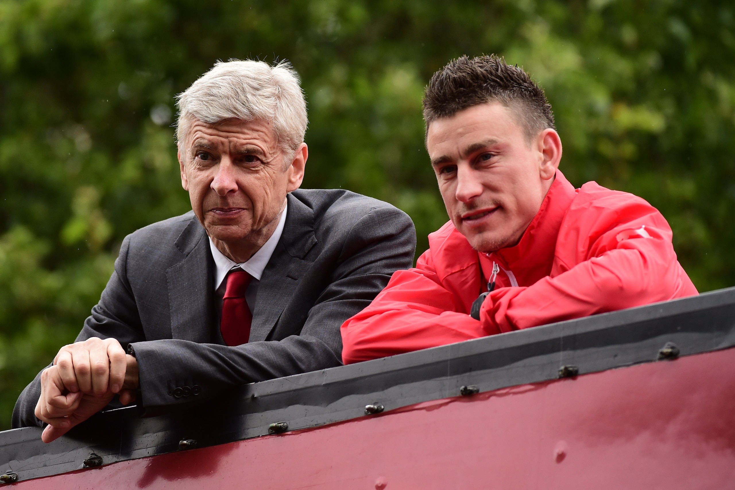 Arsenal's French manager Arsene Wenger (L) and Arsenal's French defender Laurent Koscielny look out from an open top bus during the Arsenal victory parade in London on May 31, 2015, following their win in the English FA Cup final football match on May 30,