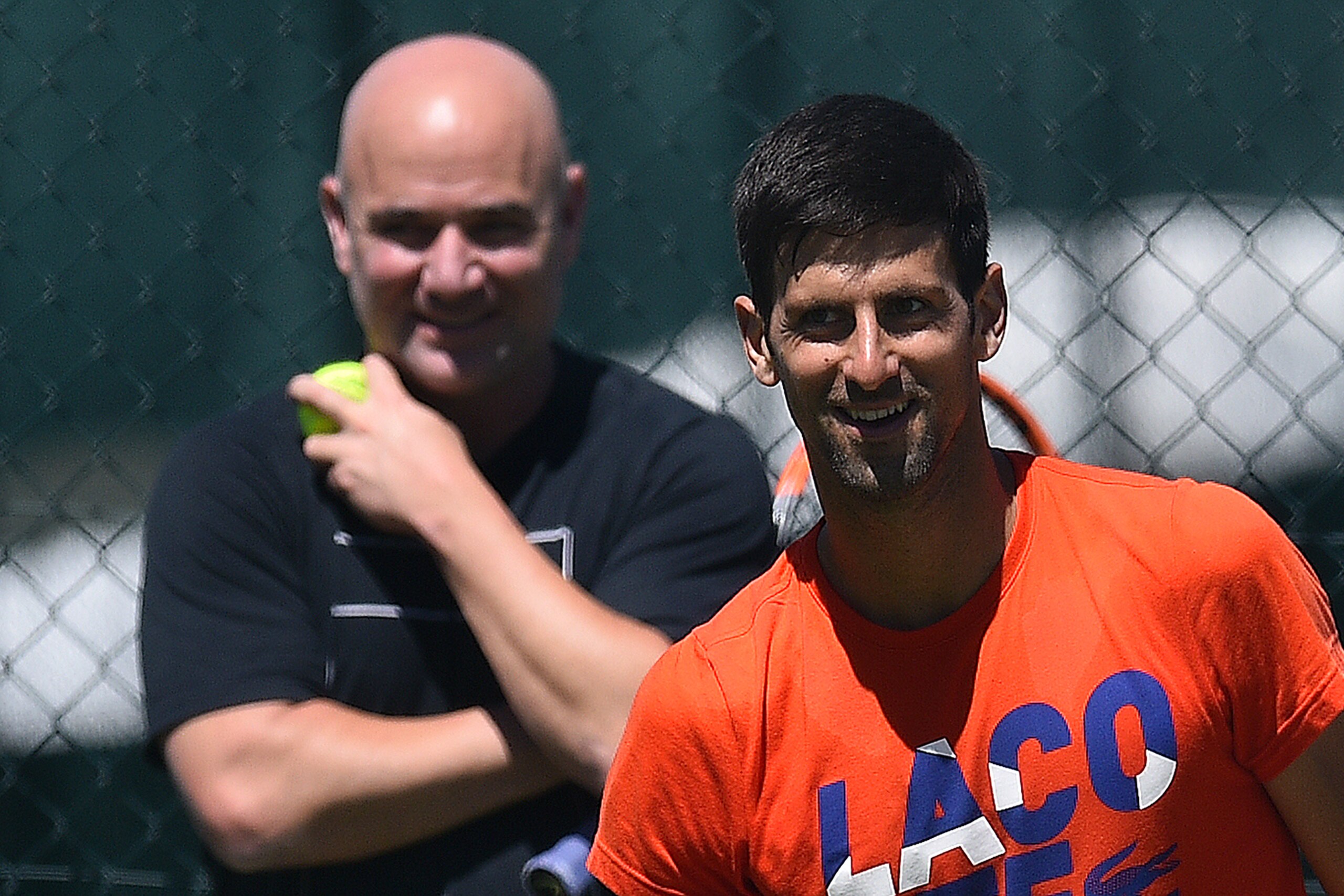 US coach Andre Agassi (L) watches Serbia's Novak Djokovic as he attends a practice session at The All England Tennis Club in Wimbledon, southwest London, on July 2, 2017, on the eve of the start of the 2017 Wimbledon Championships tennis tournament. / AFP