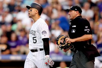 DENVER, CO - JULY 22:  Carlos Gonzalez #5 of the Colorado Rockies is restrained from going to the mound by home plate umpire Chad Fairchild in the sixth inning against the Pittsburgh Pirates at Coors Field on July 22, 2017 in Denver, Colorado.  (Photo by 