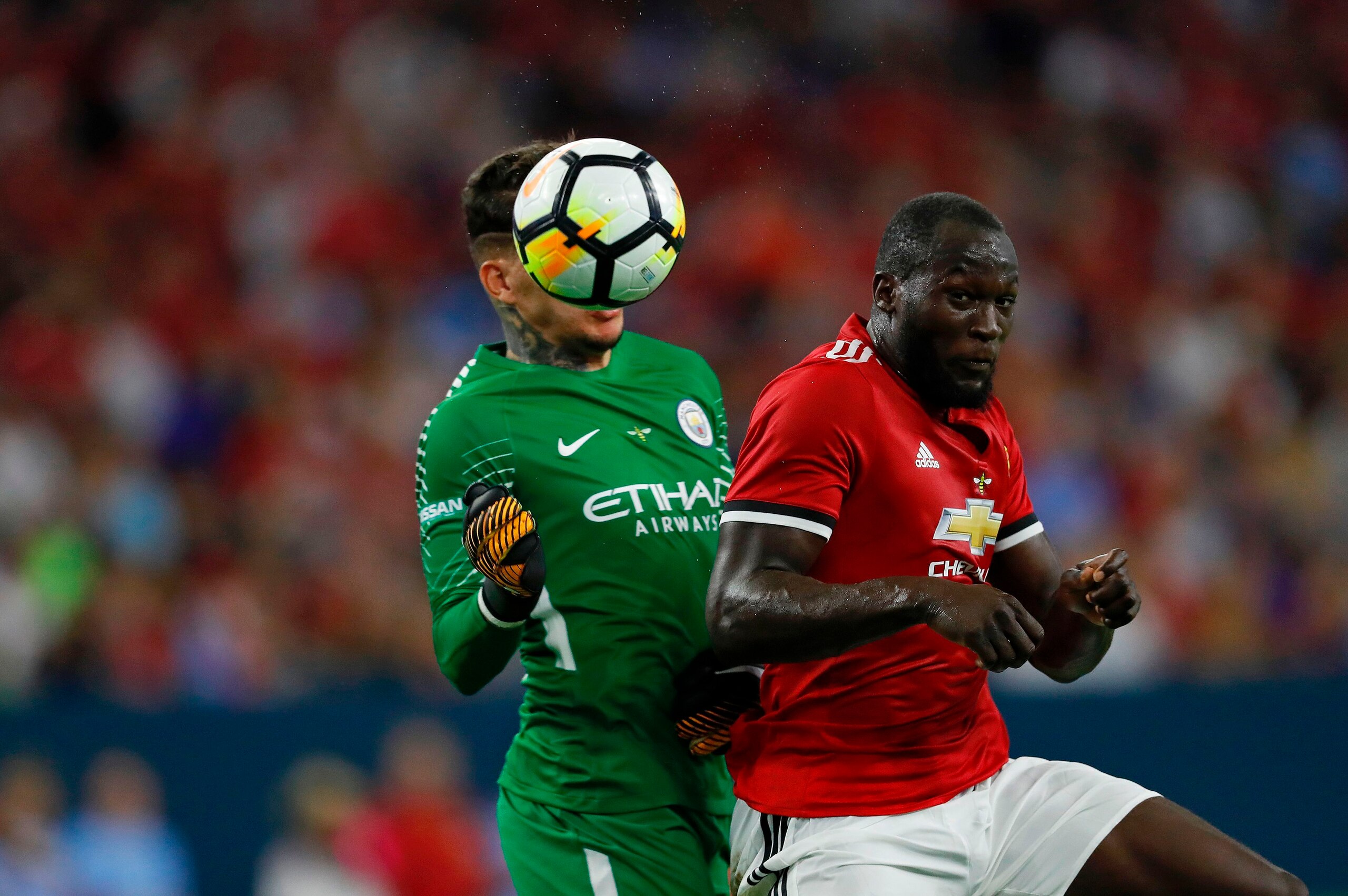 Manchester United forward Romelu Lukaku (R) hits a header past Manchester City goalkeeper Ederson Moraes (L) during the International Champions Cup soccer match at NRG Stadium on July 20, 2017 in Houston, Texas. Manchester United won 2-0. / AFP PHOTO / AA