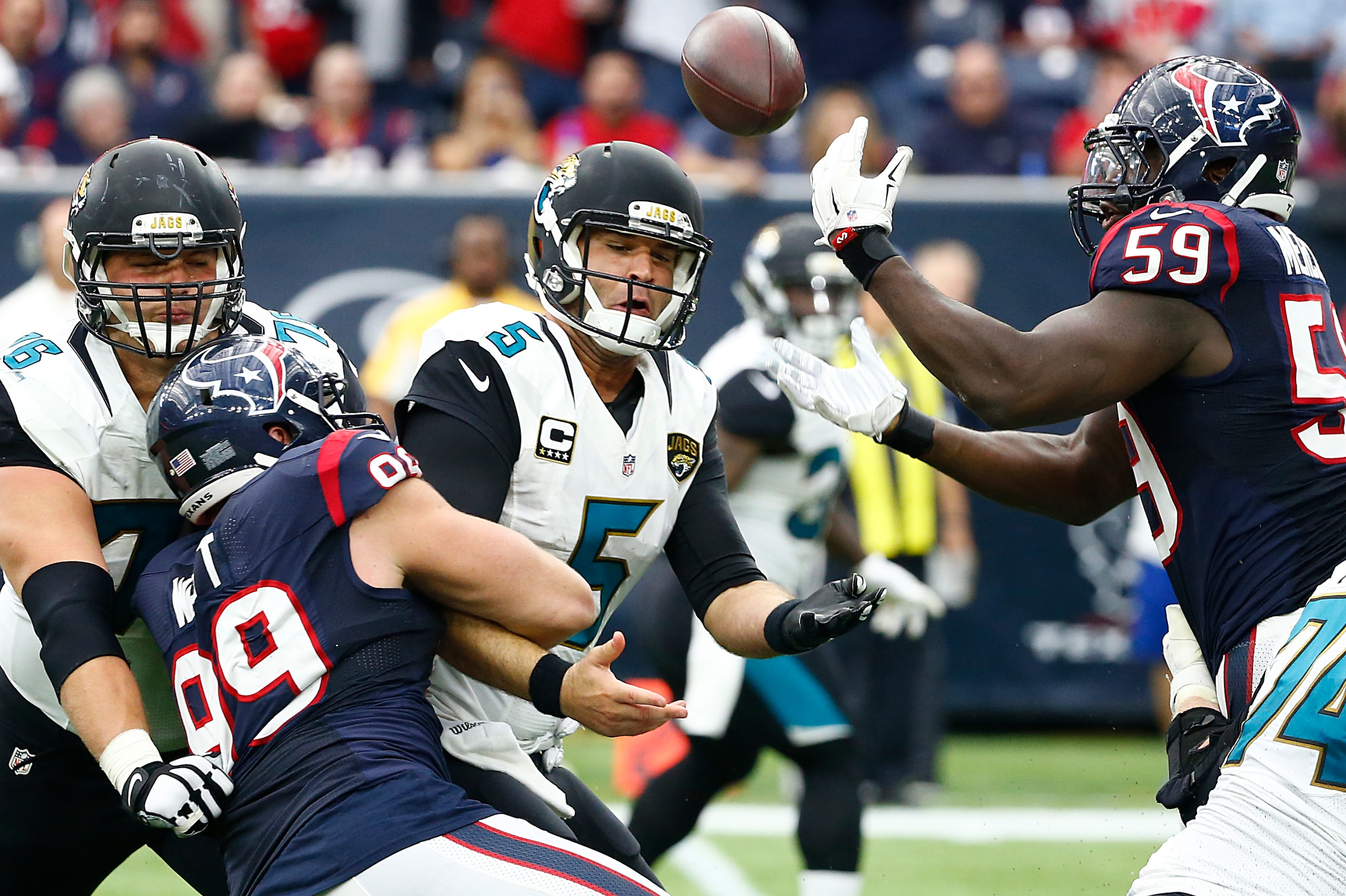 HOUSTON, TX - JANUARY 03: J.J. Watt #99 of the Houston Texans strips the ball from Blake Bortles #5 of the Jacksonville Jaguars into the hands of Whitney Mercilus #59 of the Houston Texans for an interception in the fourth quarter on January 3, 2016 at NR