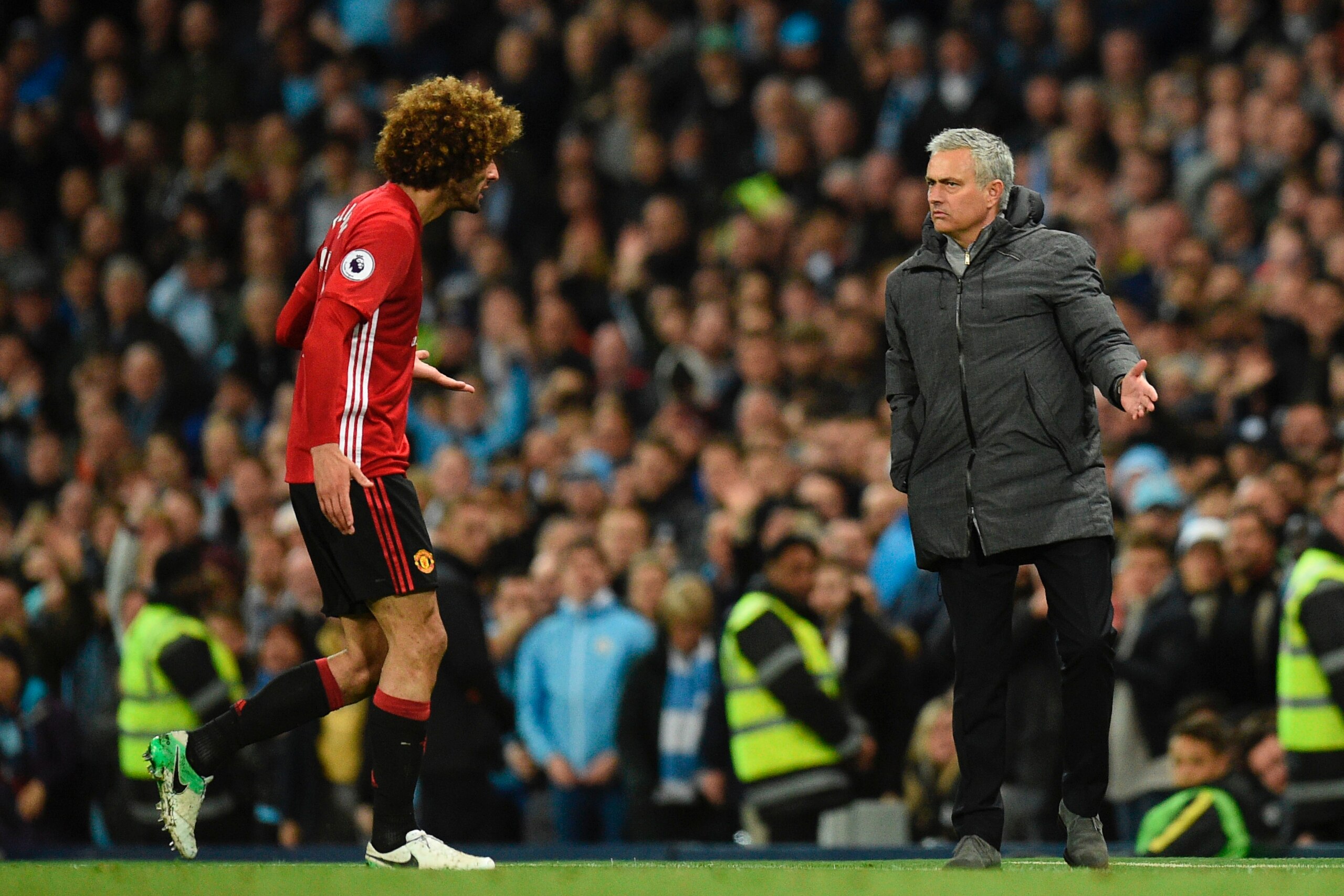 Manchester United's Belgian midfielder Marouane Fellaini (L) reacts to Manchester United's Portuguese manager Jose Mourinho (R) as he leaves the pitch after being sent off during the English Premier League football match between Manchester City and Manche