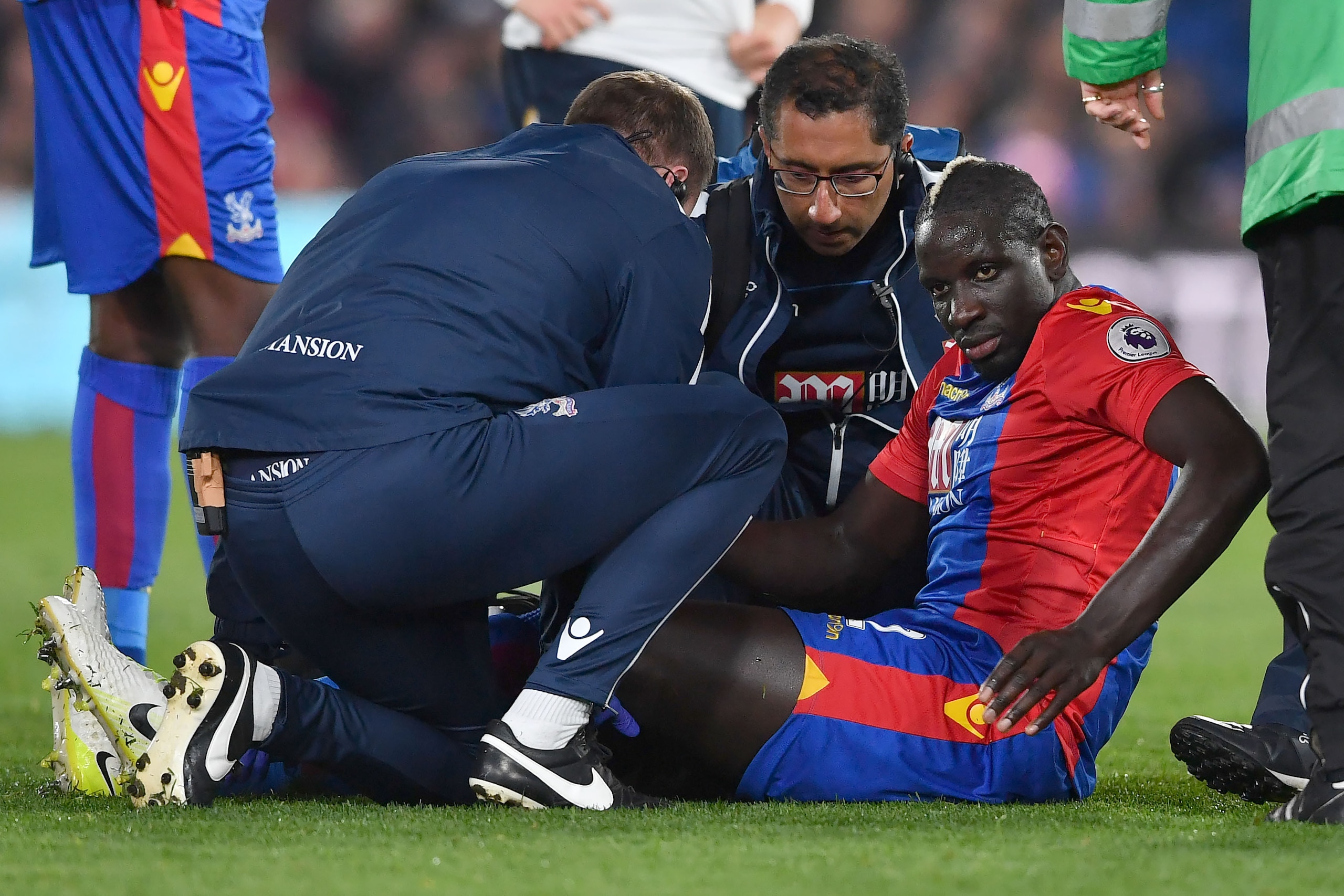 Injured Crystal Palace's French midfielder Mamadou Sakho (R) receives attention before being stretched off during the English Premier League football match between Crystal Palace and Tottenham Hotspur at Selhurst Park in south London on April 26, 2017. / 