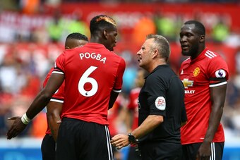 Referee Jonathon Moss (C) talks to Manchester United's French midfielder Paul Pogba (L) as Manchester United's Belgian striker Romelu Lukaku looks on during the English Premier League football match between Swansea City and Manchester United at The Libert