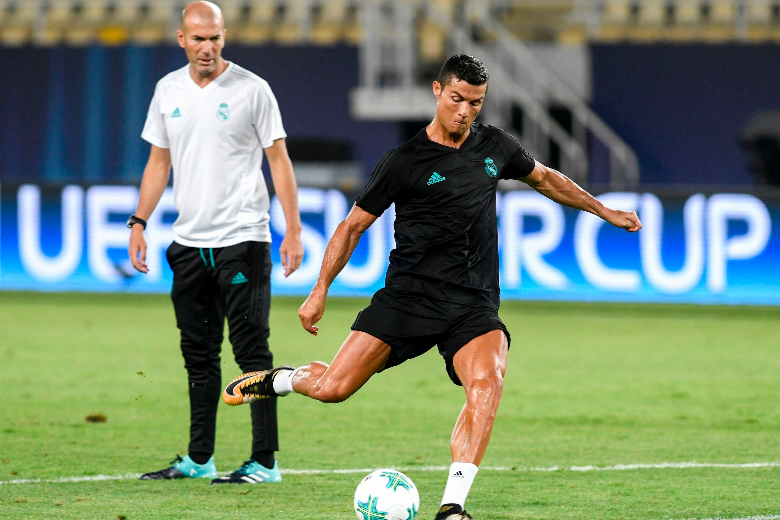 TOPSHOT - Real Madrid's French head coach Zinedine Zidane (L) looks on as Real Madrid's forward Cristiano Ronaldo shoots the ball during a training session before the UEFA Super Cup 2017 football match between Real Madrid and Manchester United at the Nati