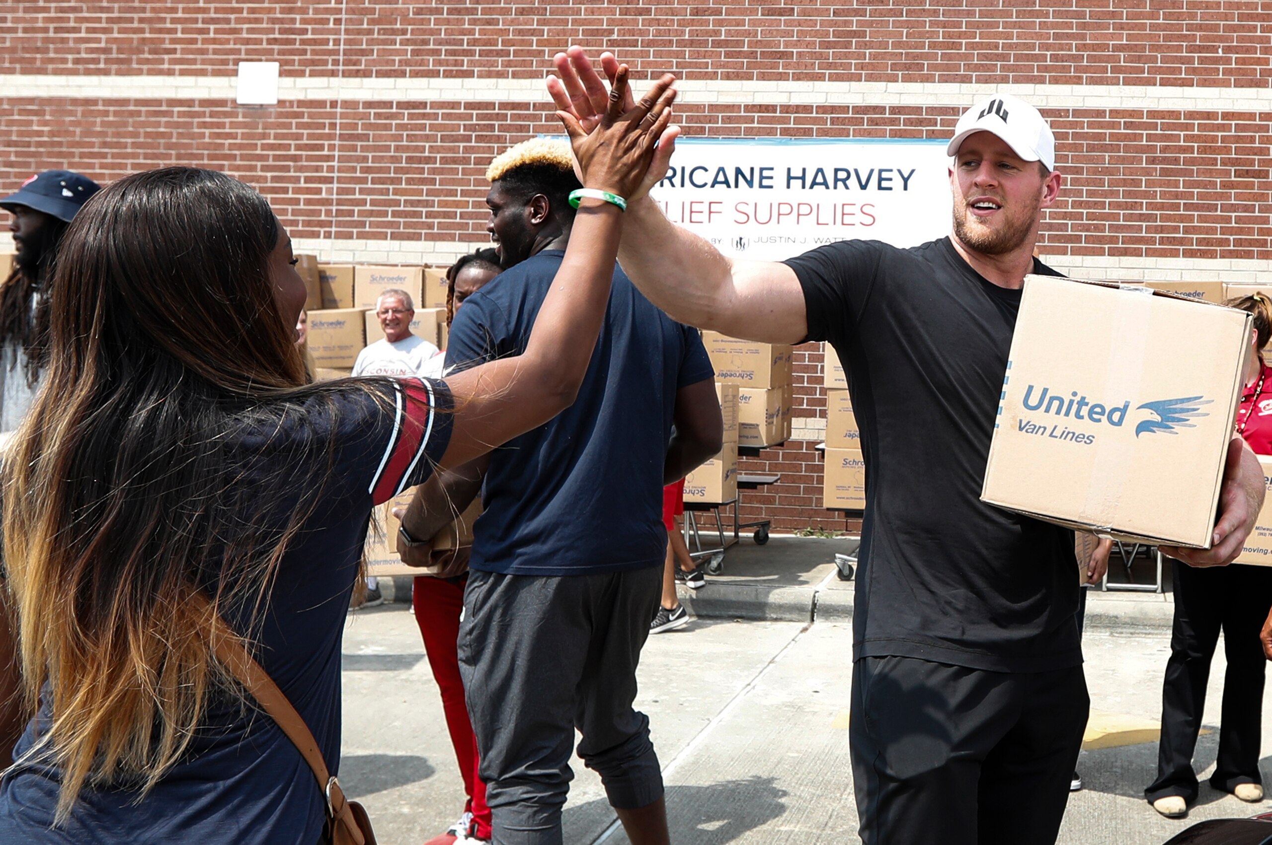 HOUSTON, TX - SEPTEMBER 3: (AFP OUT) Anna Ucheomumu high fives Houston Texans defensive end J.J. Watt after loading a car with relief supplies for people impacted by Hurricane Harvey on September 3, 2017, in Houston, Texas. J.J. Watt's Hurricane Harvey Re
