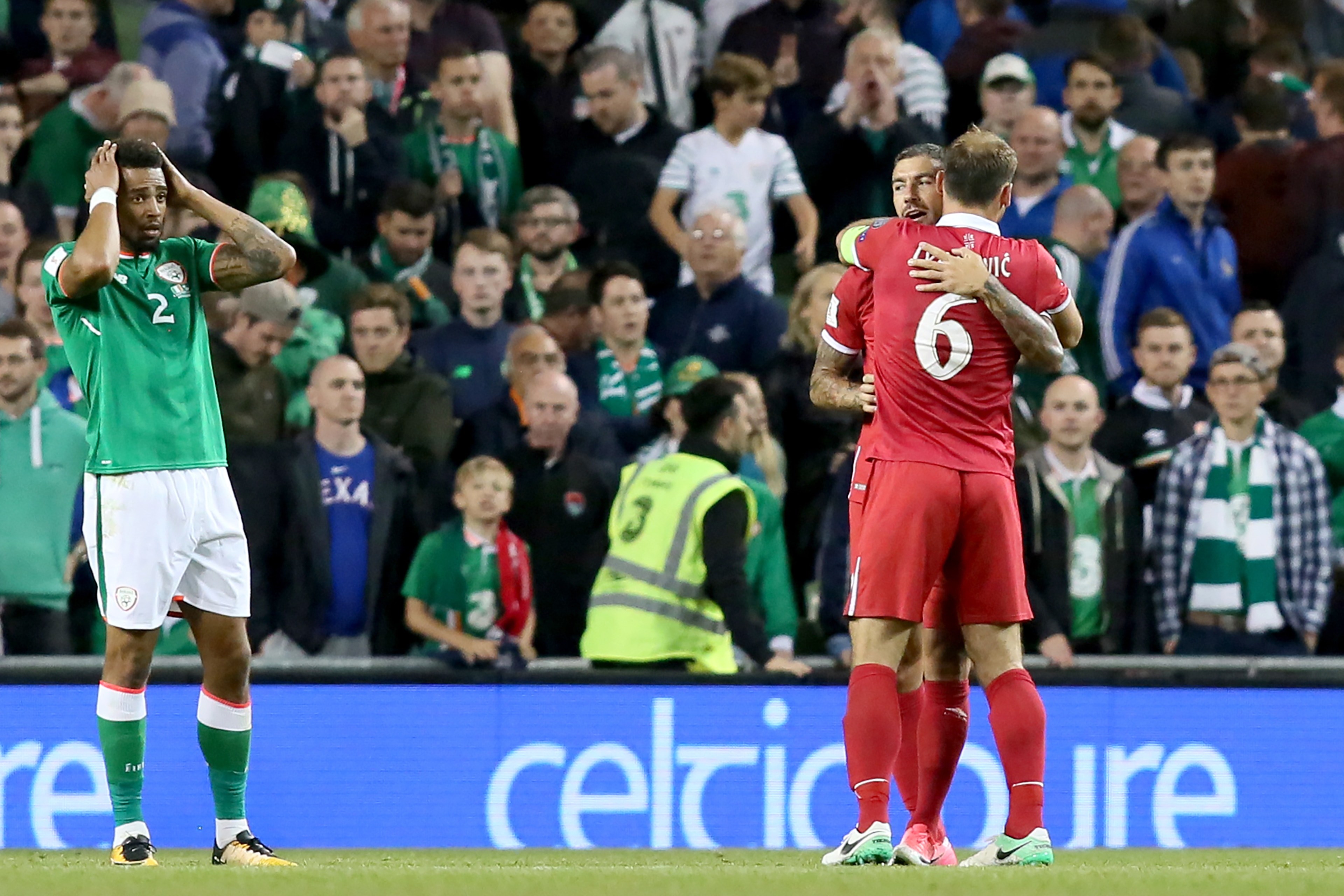Serbia's defender Aleksandar Kolarov and Serbia's defender Branislav Ivanovic (R) embrace as Republic of Ireland's defender Cyrus Christie reacts to Ireland's defeat at the final whistle in the World Cup 2018 qualification football match between Republic 