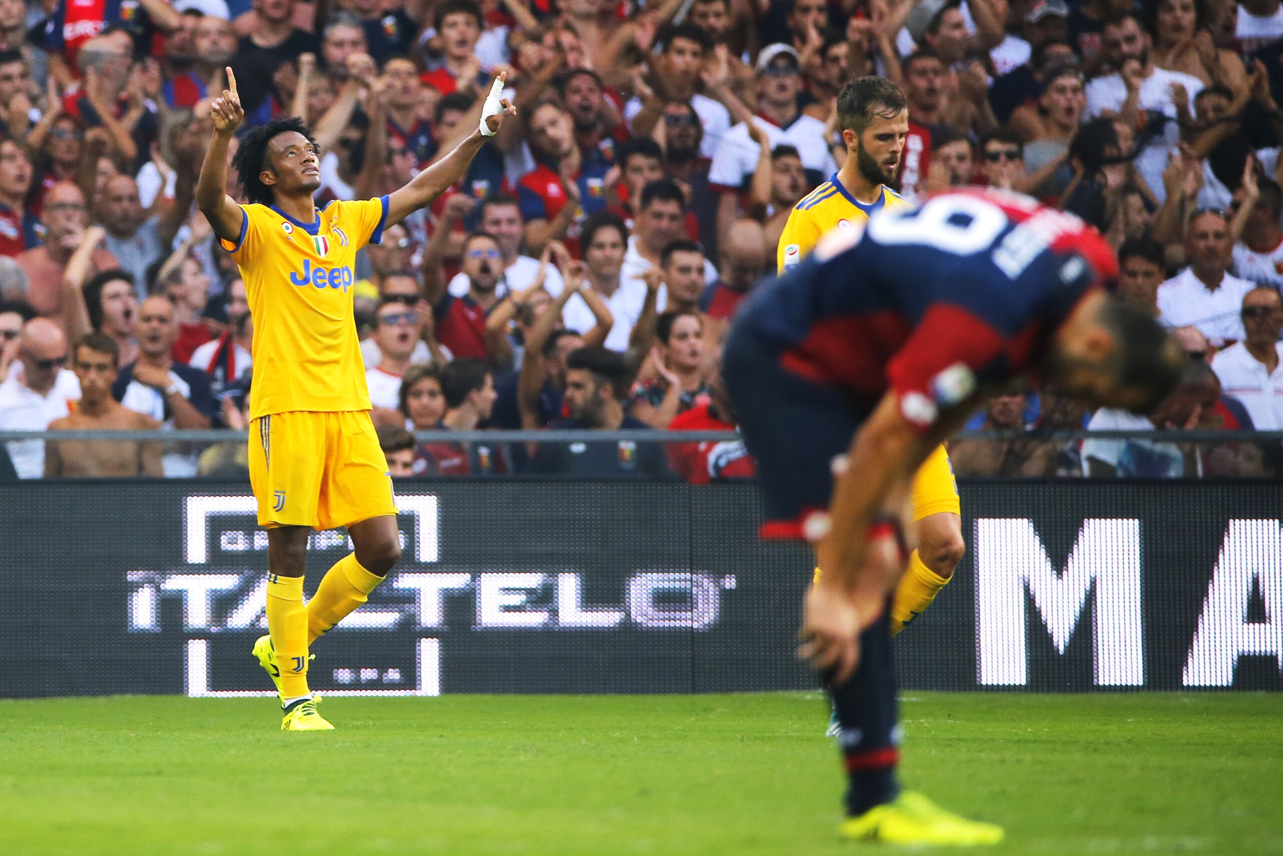 Juventus' Colombian midfielder Juan Cuadrado (L) celebrates after scoring during the Italian Serie A football match Genoa v Juventus at The Luigi Ferraris Stadium in Genoa on August 26, 2017. / AFP PHOTO / Marco BERTORELLO        (Photo credit should read