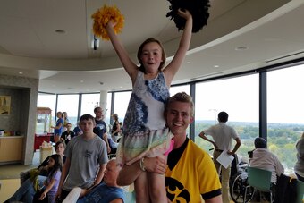 An Iowa cheerleader lifts a child in the Press Box