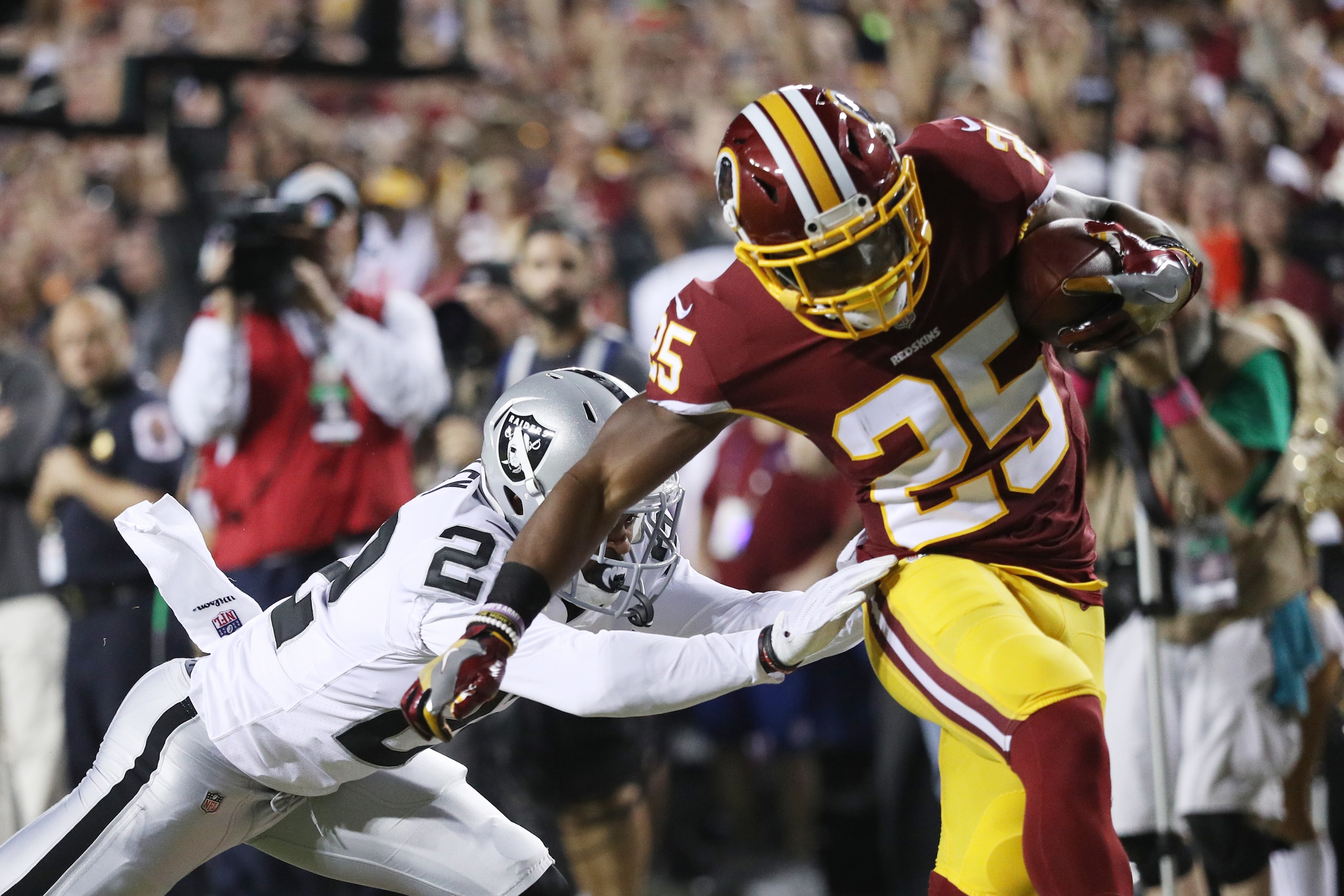 LANDOVER, MD - SEPTEMBER 24: Running back Chris Thompson #25 of the Washington Redskins scores a touchdown as cornerback Chris Thompson #22 of the Oakland Raiders tries to stop him in the first quarter at FedExField on September 24, 2017 in Landover, Mary