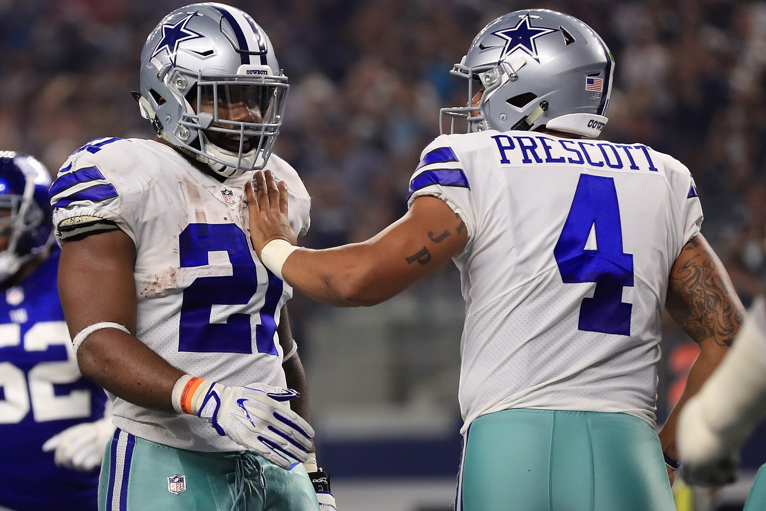 ARLINGTON, TX - SEPTEMBER 10:  Ezekiel Elliott #21 of the Dallas Cowboys gets pat on the chest from Dak Prescott #4 of the Dallas Cowboys in the first half of a game against the New York Giants  at AT&T Stadium on September 10, 2017 in Arlington, Texas.  