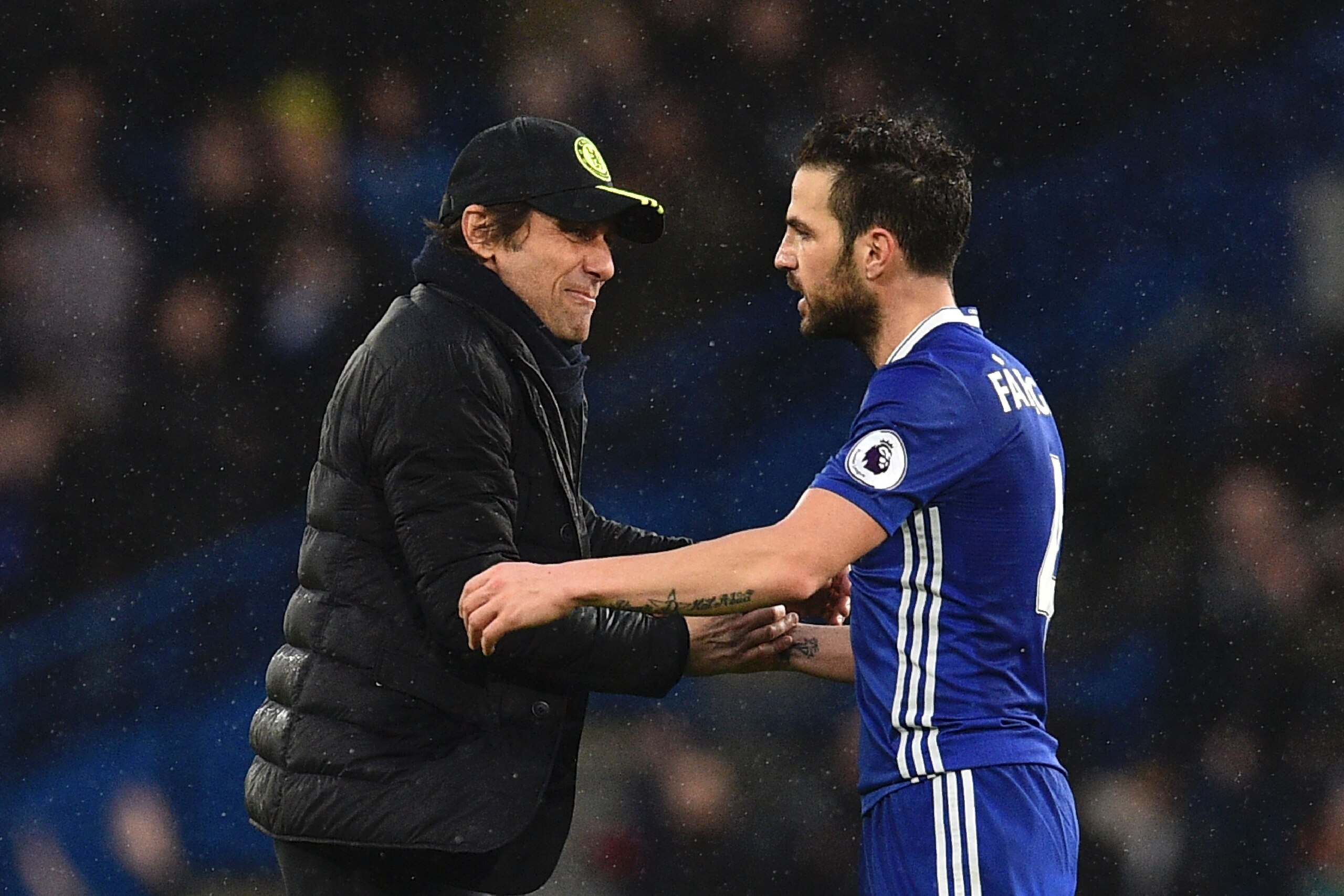 Chelsea's Italian head coach Antonio Conte (L) shakes hands with Chelsea's Spanish midfielder Cesc Fabregas (R) on the pitch at the end of the English Premier League football match between Chelsea and Swansea at Stamford Bridge in London on February 25, 2