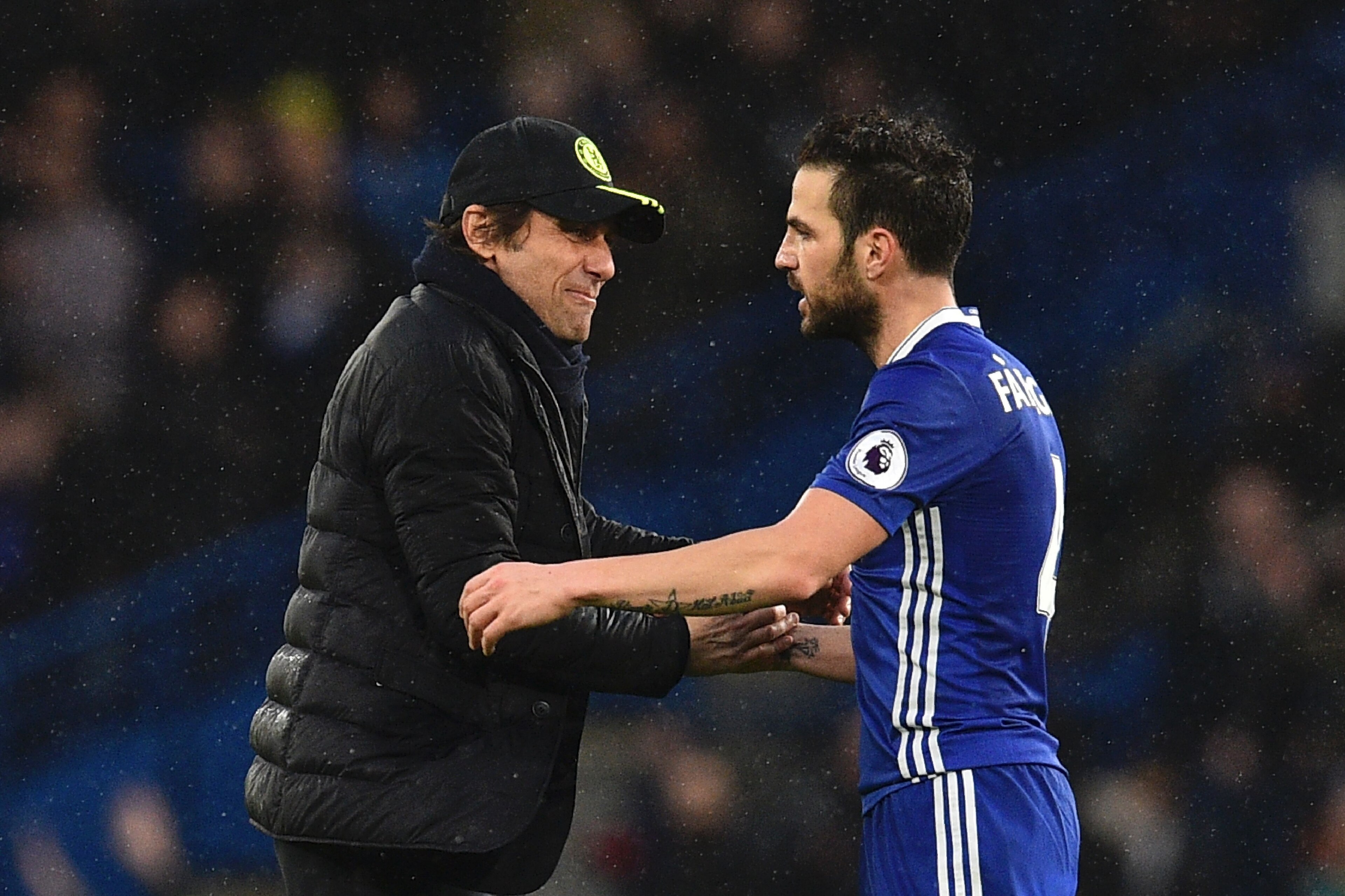 Chelsea's Italian head coach Antonio Conte (L) shakes hands with Chelsea's Spanish midfielder Cesc Fabregas (R) on the pitch at the end of the English Premier League football match between Chelsea and Swansea at Stamford Bridge in London on February 25, 2