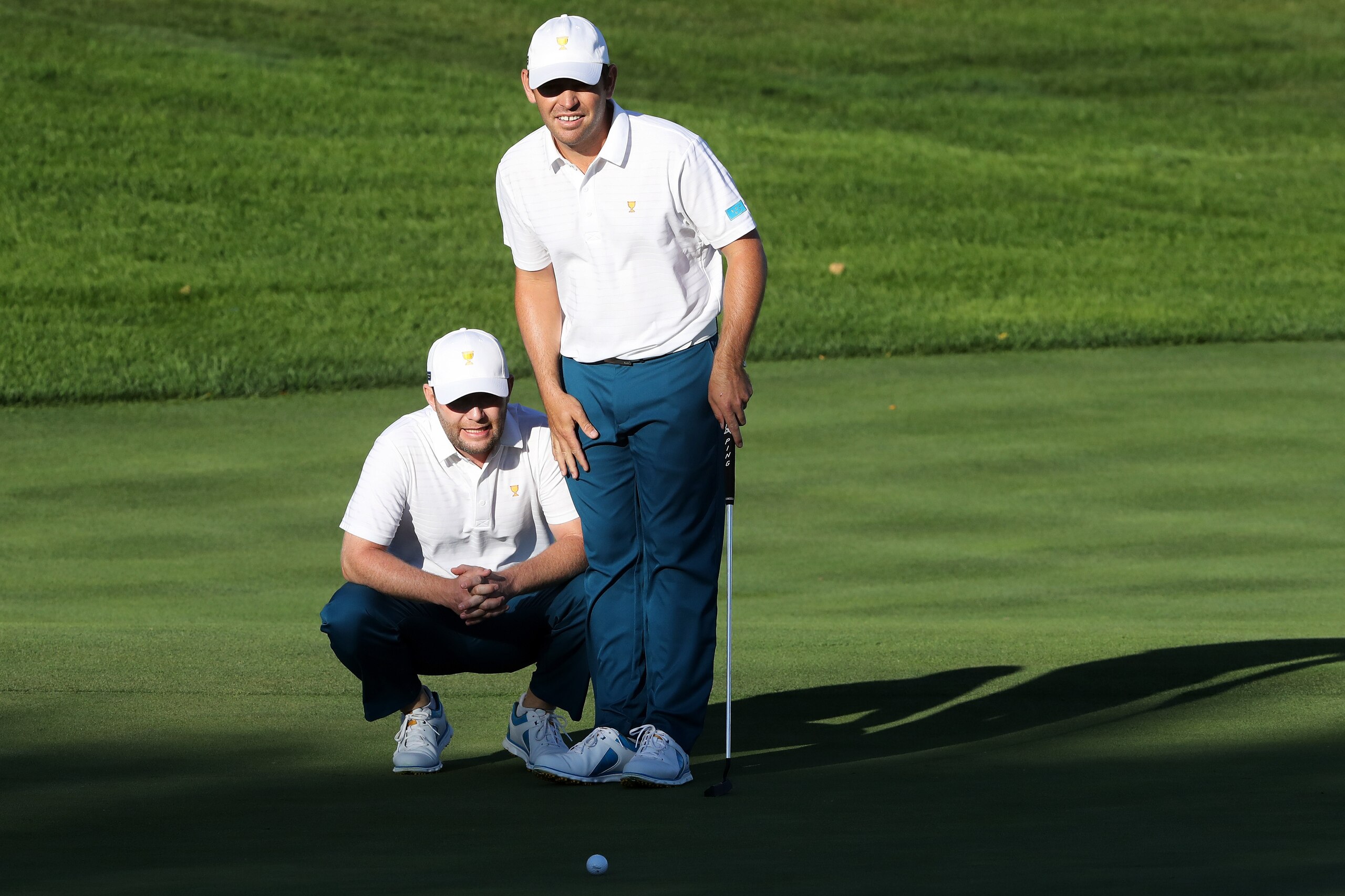 JERSEY CITY, NJ - SEPTEMBER 28:  Branden Grace and Louis Oosthuizen of South Africa and the International Team line up a putt during Thursday foursome matches of the Presidents Cup at Liberty National Golf Club on September 28, 2017 in Jersey City, New Je