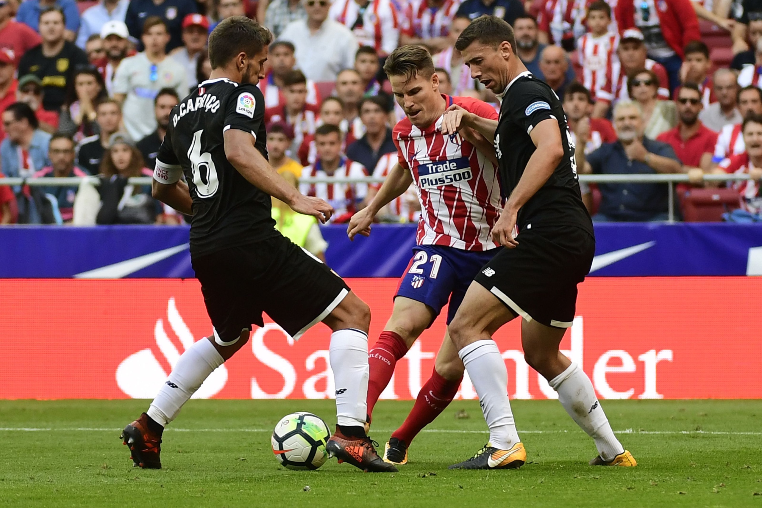 Atletico Madrid's forward from France Kevin Gameiro (C) vies with Sevilla's defender from France Clement Lenglet (R) and Sevilla's midfielder from Portugal Daniel Carrico during the Spanish league football match Club Atletico de Madrid vs Sevilla FC at th